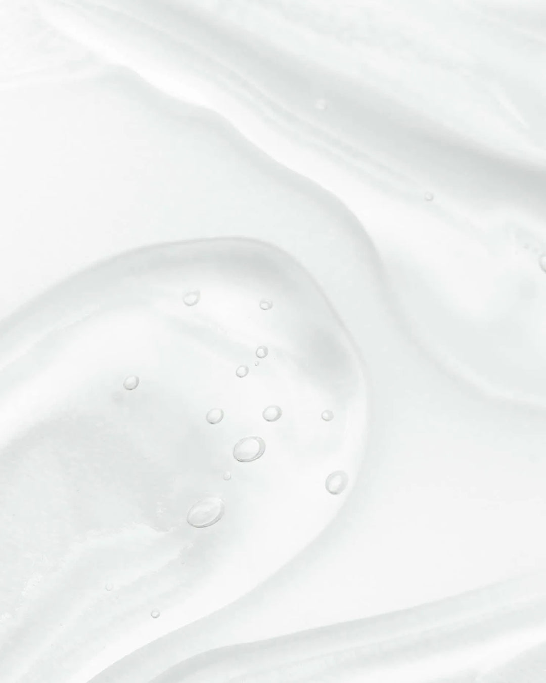 Close-up of white cream with bubbles on a light gray background