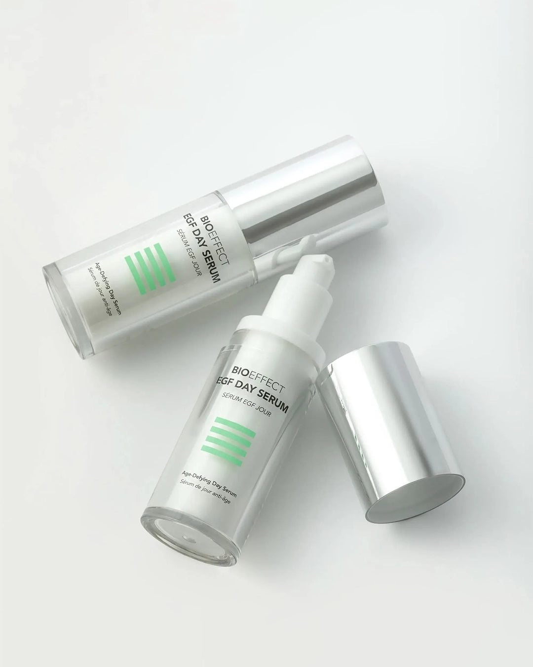 Two skincare serum bottles with caps on a white background