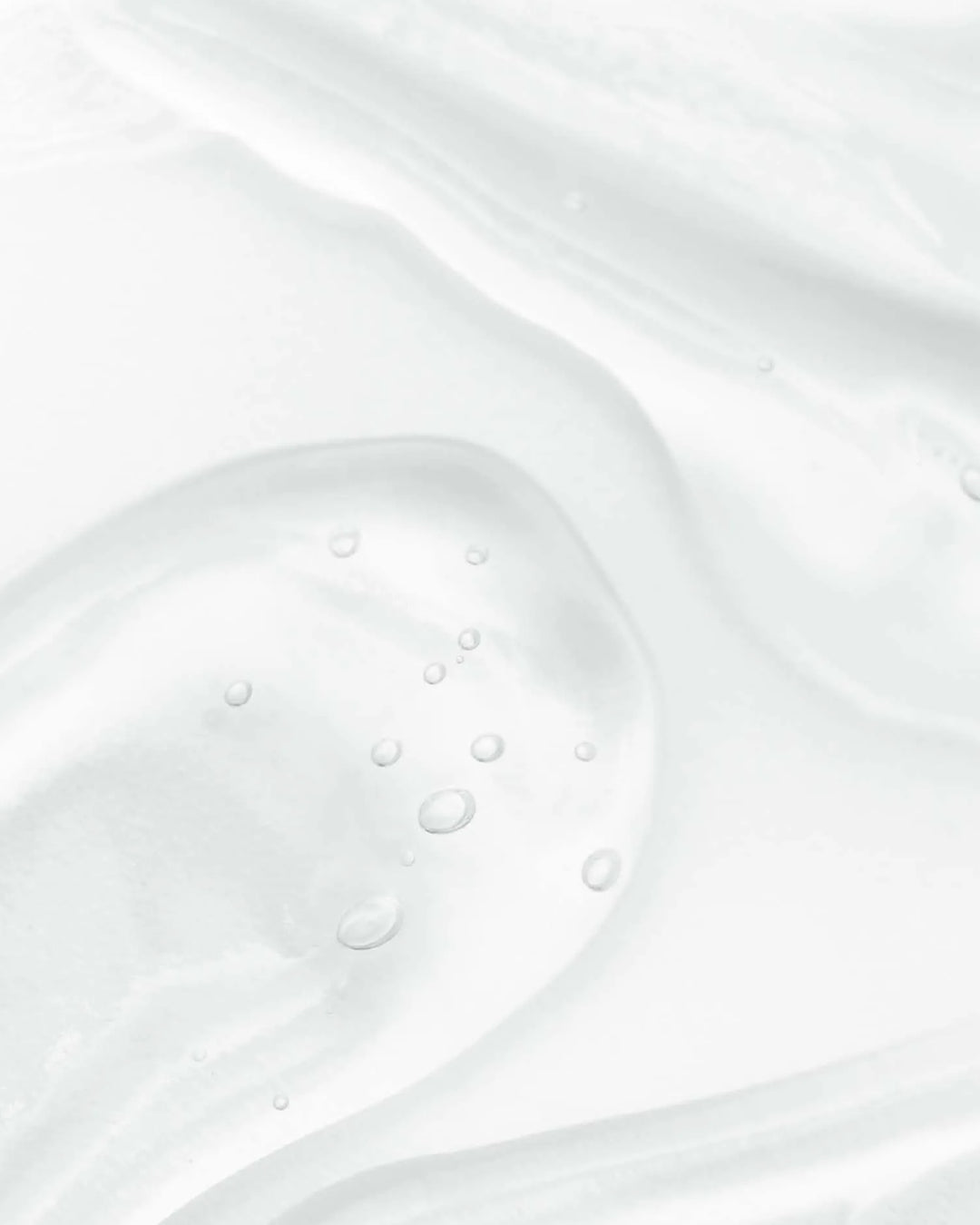 Close-up of white cream with visible bubbles on a light gray background