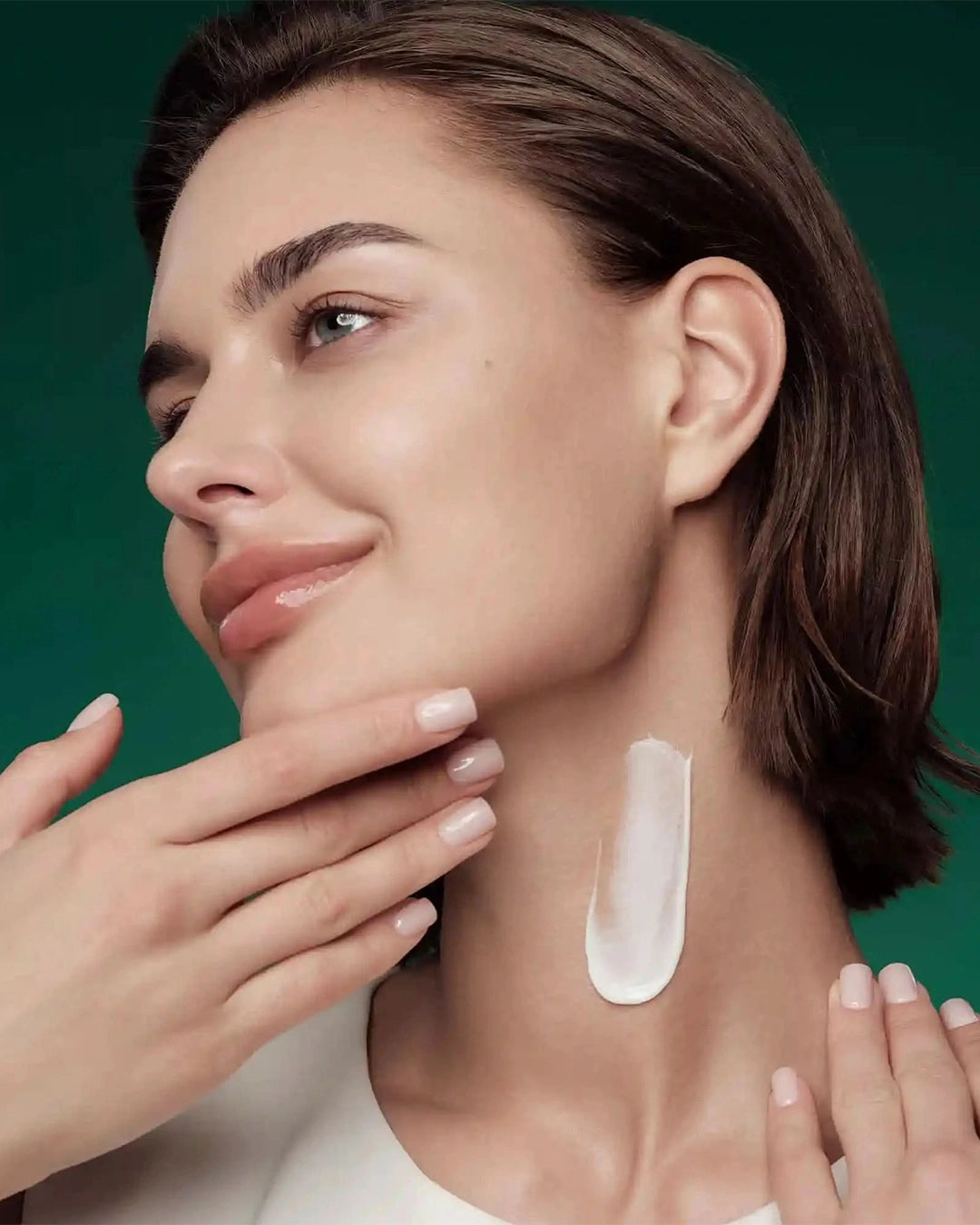 Woman with a neck cream application on a green background