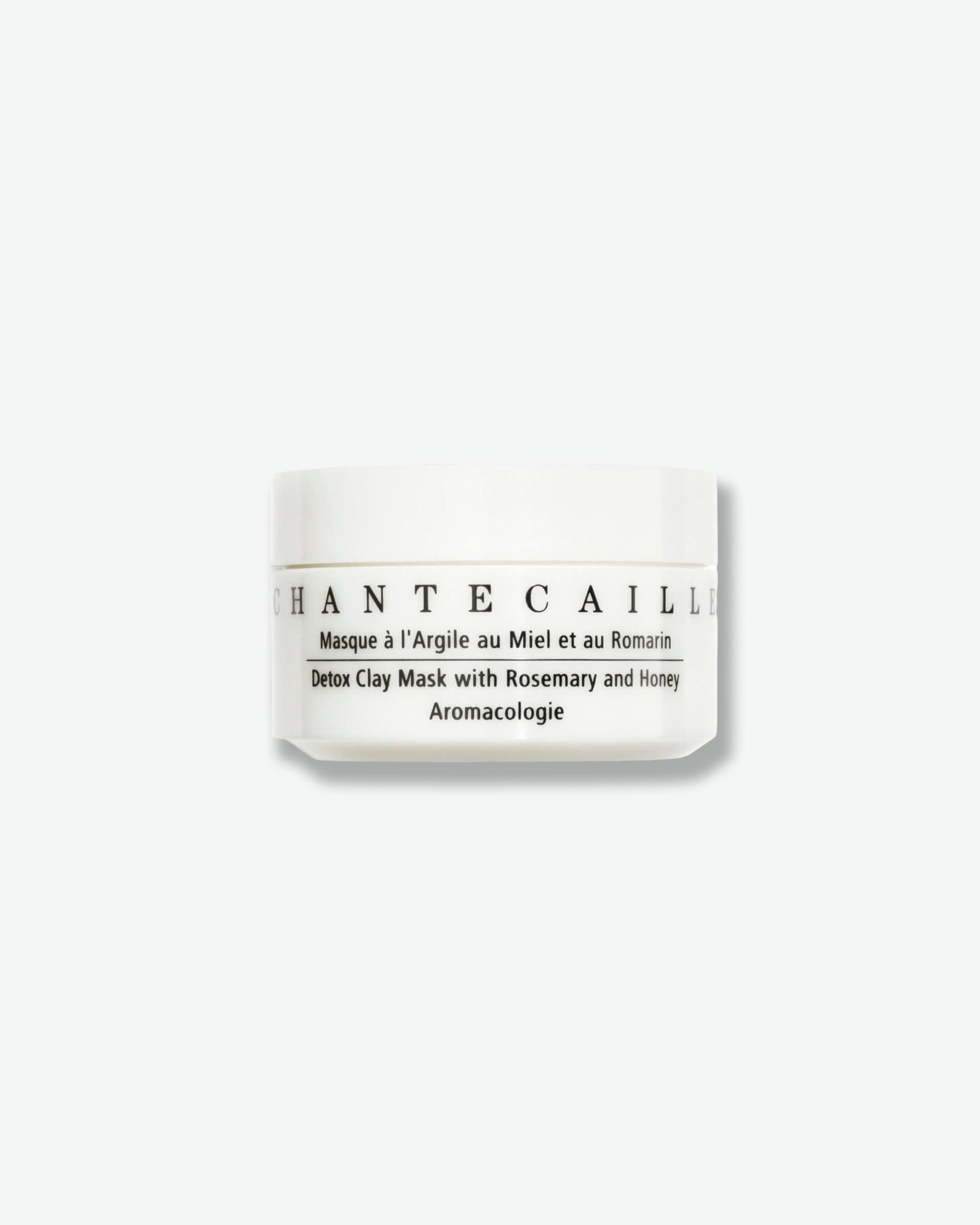 Front view of a Chantecaille Detox Clay Mask jar against a plain gray background. The compact, cylindrical skincare jar is completely opaque white with black branding and product details listed across the center.