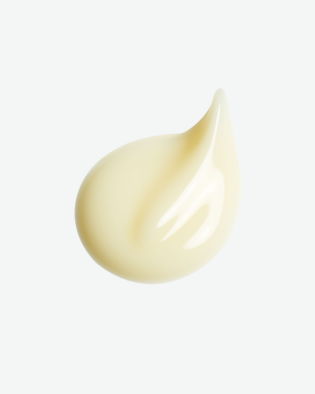 Close-up of Clé de Peau Beauté Supreme Wrinkle Smoothing Serum texture in a pale yellow cream droplet.