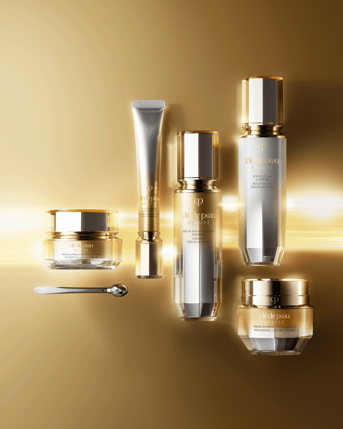 Clé de Peau Beauté Supreme skincare collection arranged against a luminous gold background.
