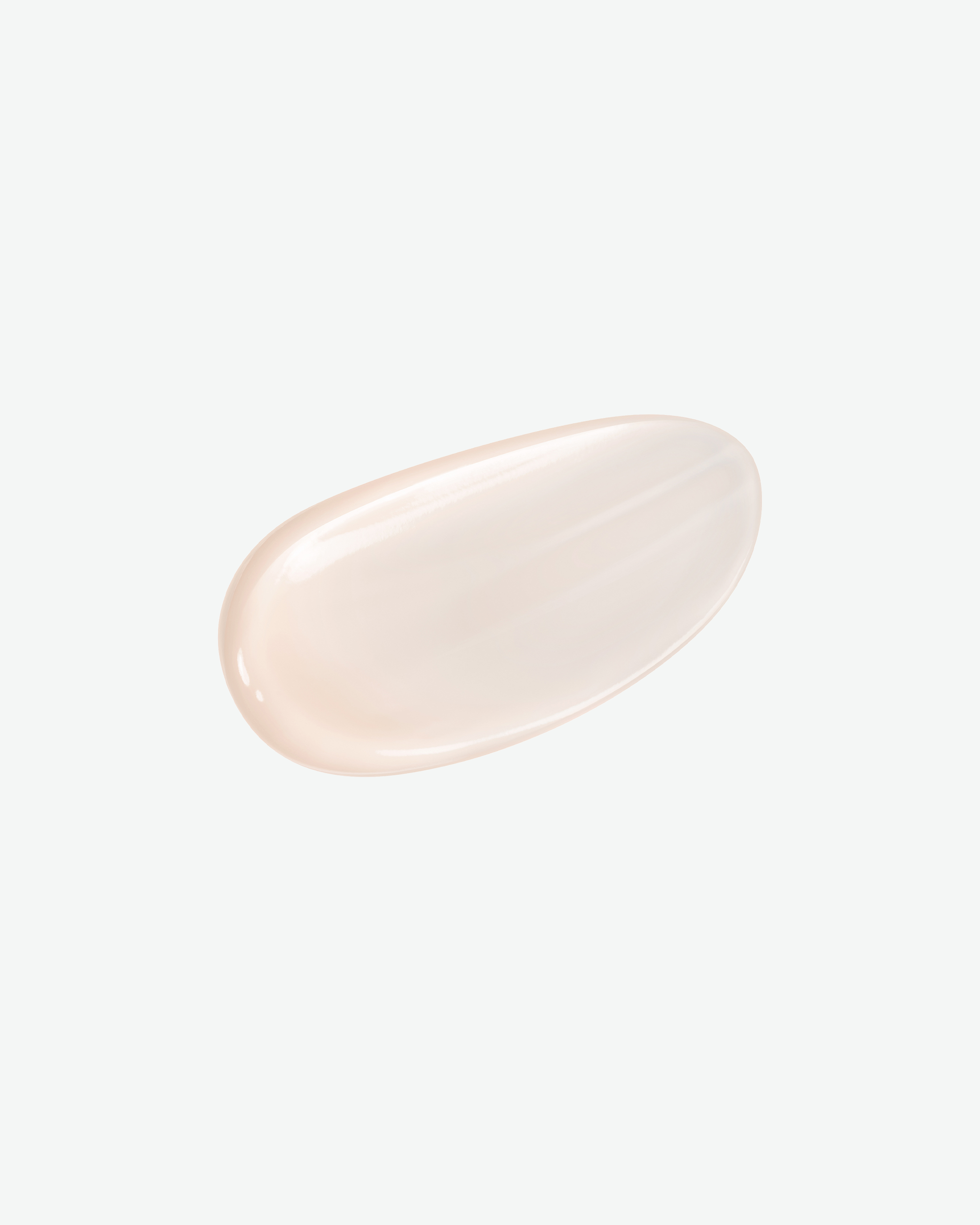 A smooth, glossy, translucent oval swatch of a pale peach-beige cosmetic cream or gel, centered on a clean, solid off-white background.