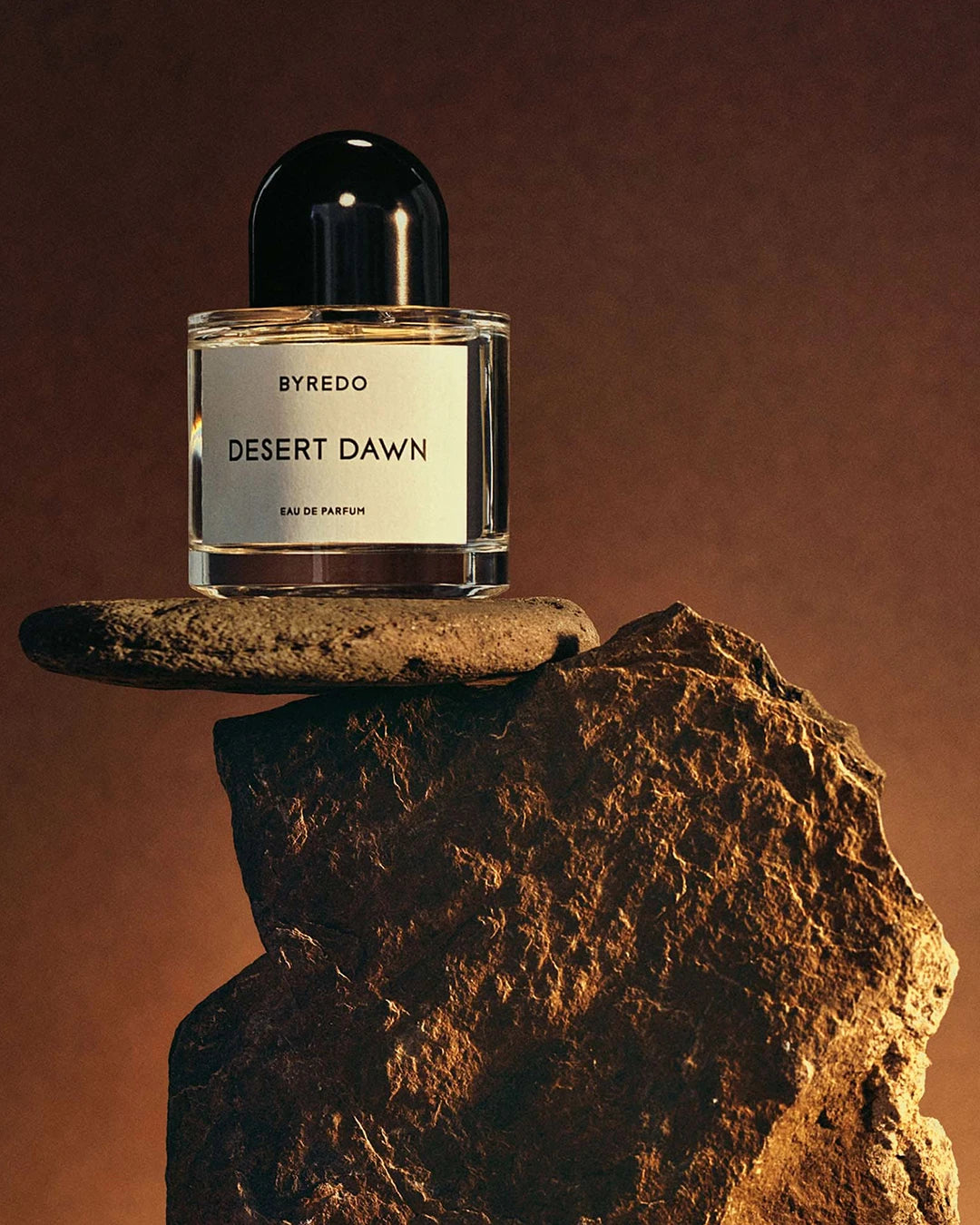 Byredo Desert Dawn perfume bottle on a stone surface with a brown background
