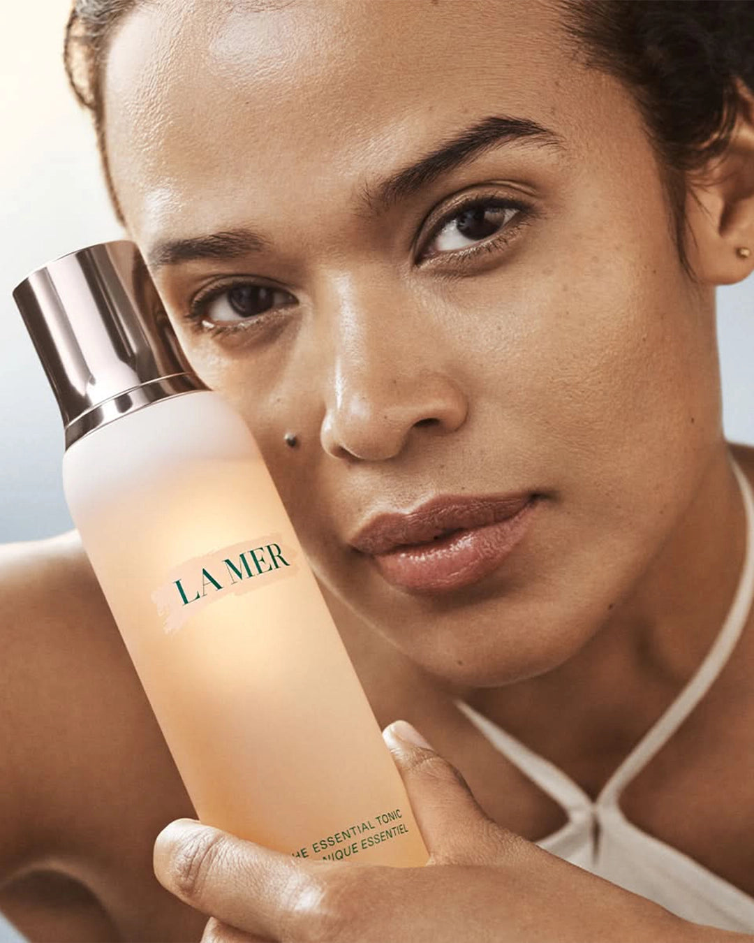 Woman holding a La Mer bottle with a blurred background