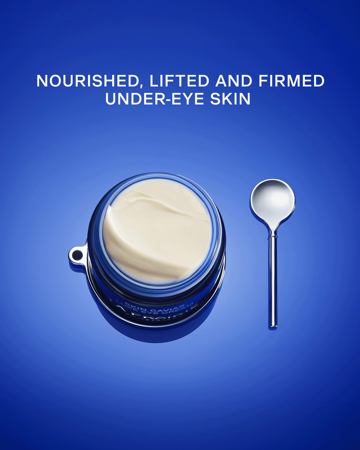 An open round jar of cream under-eye product with a blue rim and a small metal spoon on a blue gradient background, with the text 'NOURISHED, LIFTED AND FIRMED UNDER-EYE SKIN' above it.