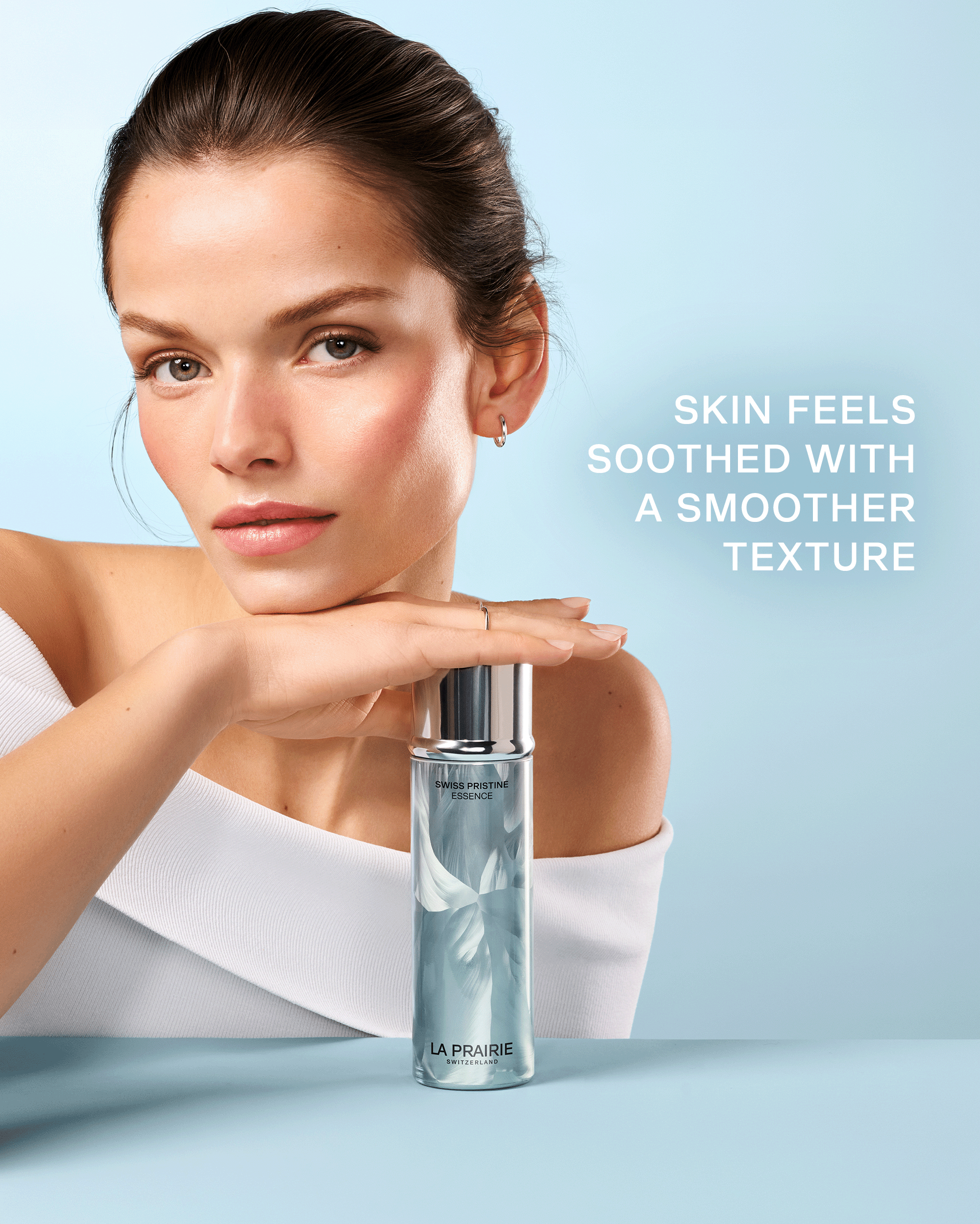 Model posed with Swiss Pristine Essence with text highlighting soothed skin and a smoother-looking texture.