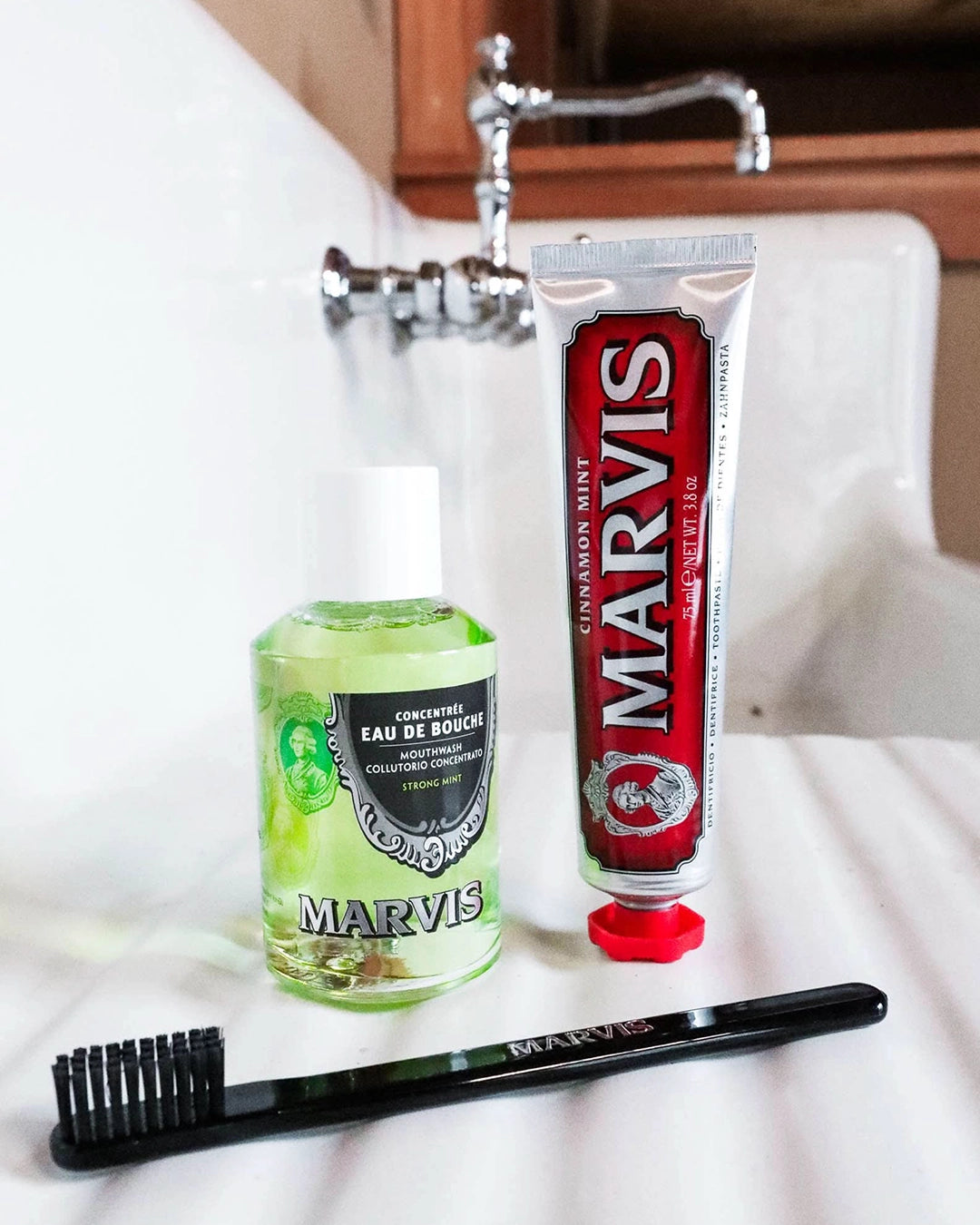 Marvis toothpaste, mouthwash, and toothbrush on a bathroom counter.
