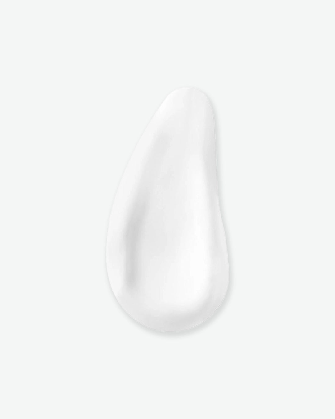 Close-up of a white cream or lotion droplet on a light gray background