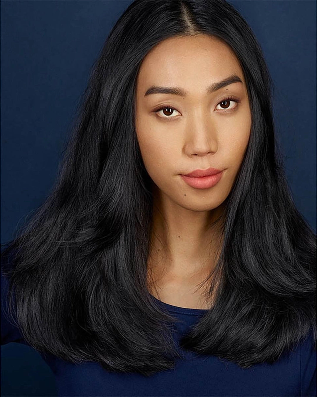 Woman with long black hair against a blue background
