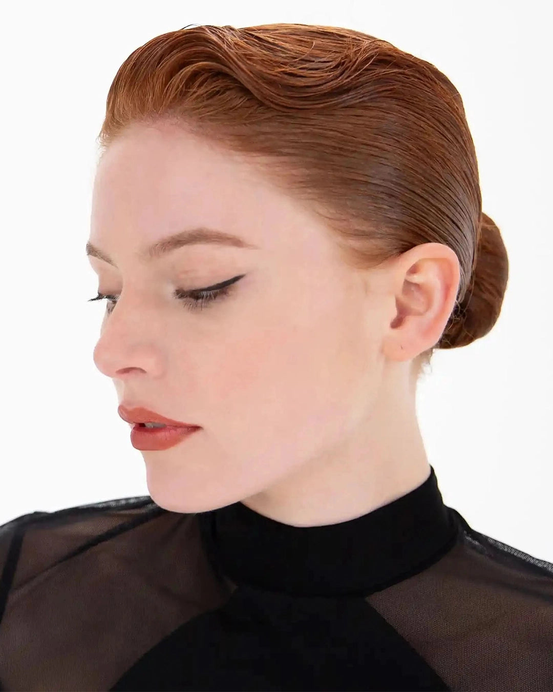 Woman with styled hair and black sheer top on a white background