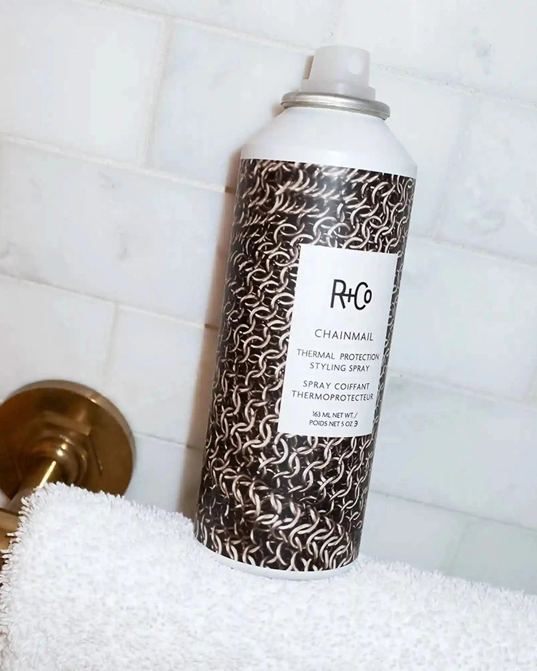 R+Co Chainmail spray can on a towel with tiled wall background