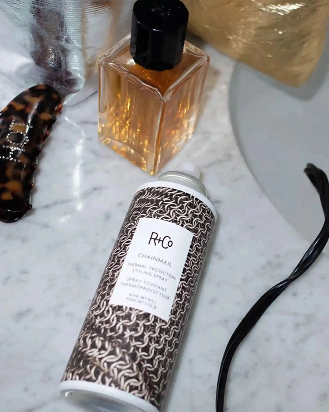R+Co hair product can and bottle on a marble surface