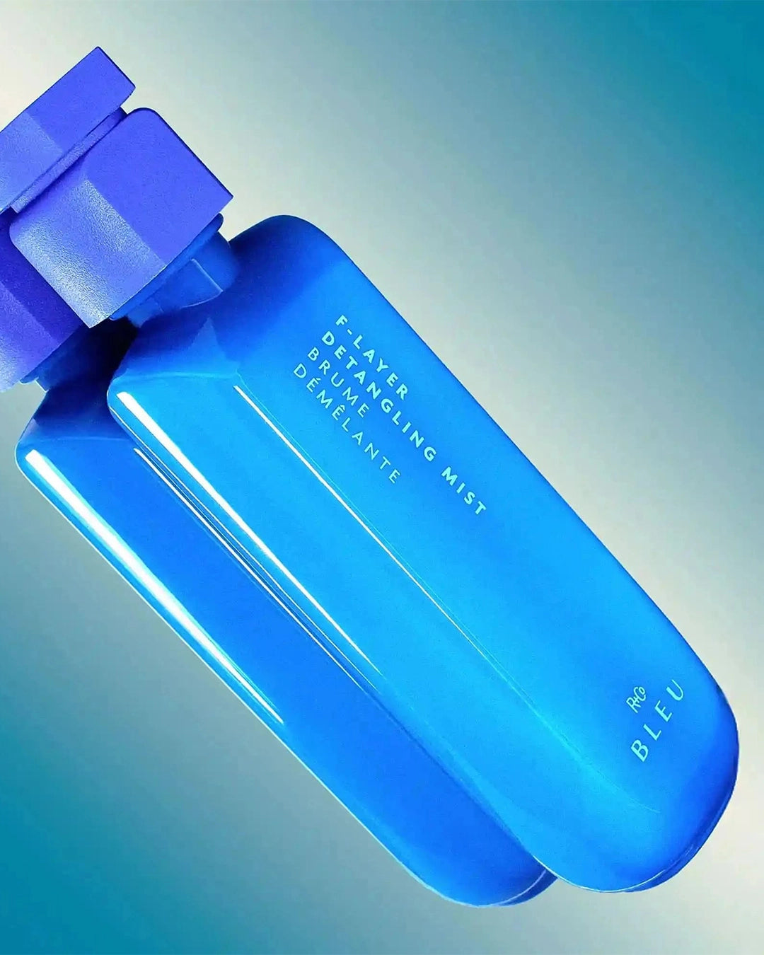 Blue detangling mist bottle with a gradient blue background
