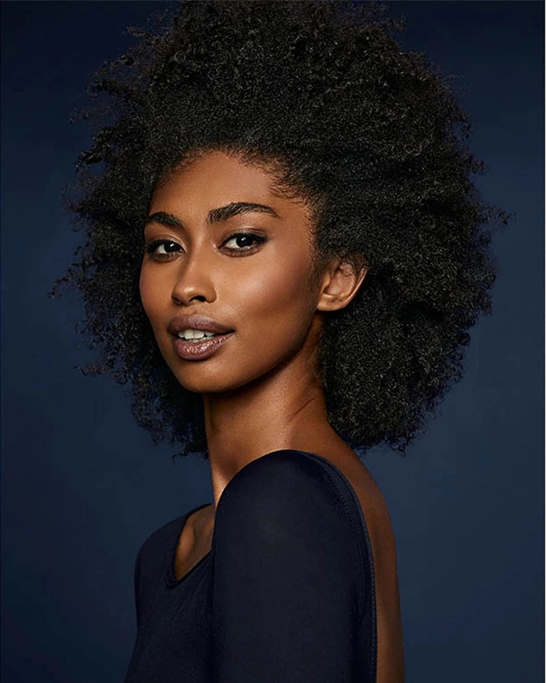 Woman with an afro hairstyle against a dark blue background