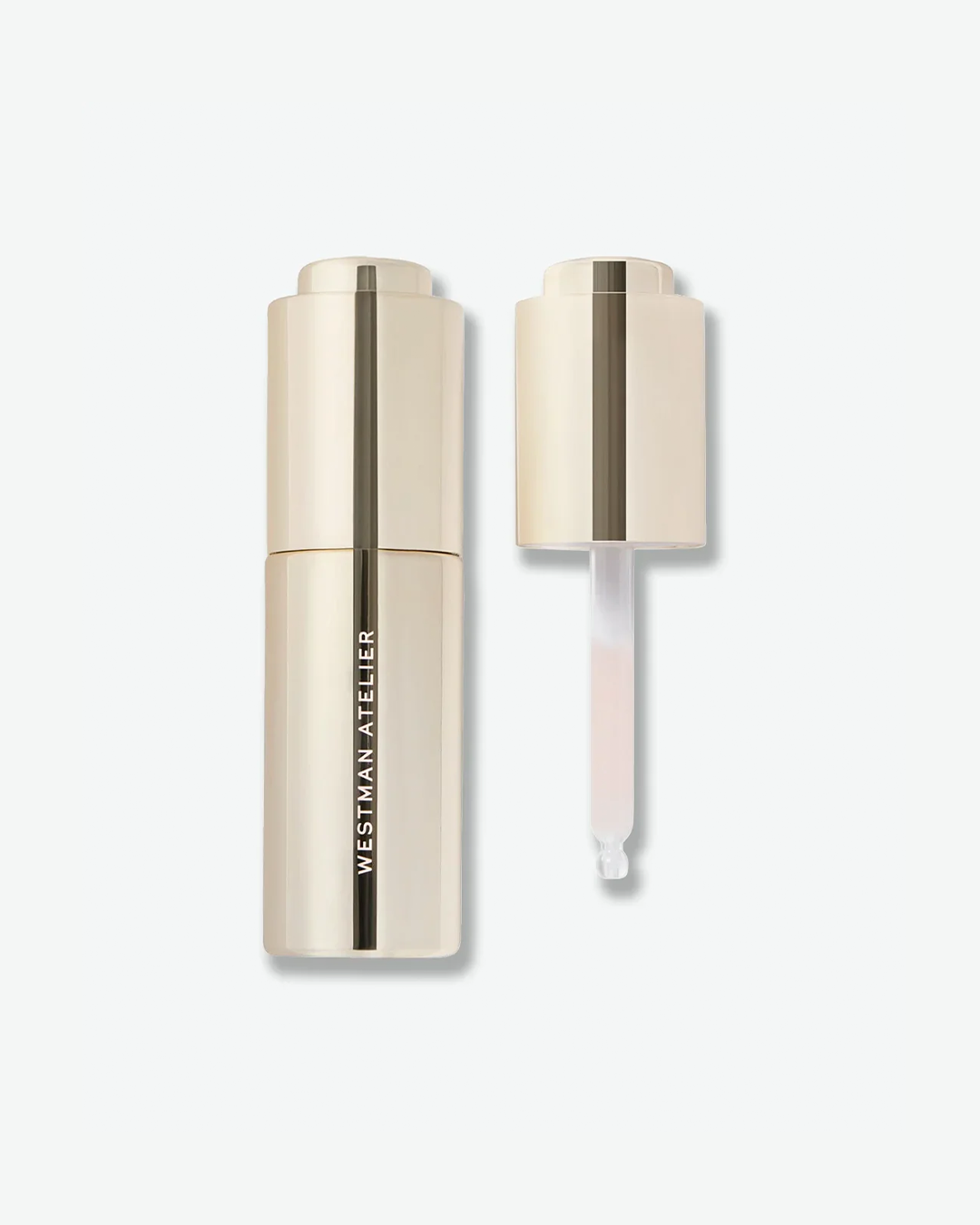 Westman Atelier liquid product in a sleek, all-gold metallic bottle shown alongside its unscrewed dropper cap, revealing a clear glass pipette with a subtle pink-tinted formula, isolated on a light grey background.