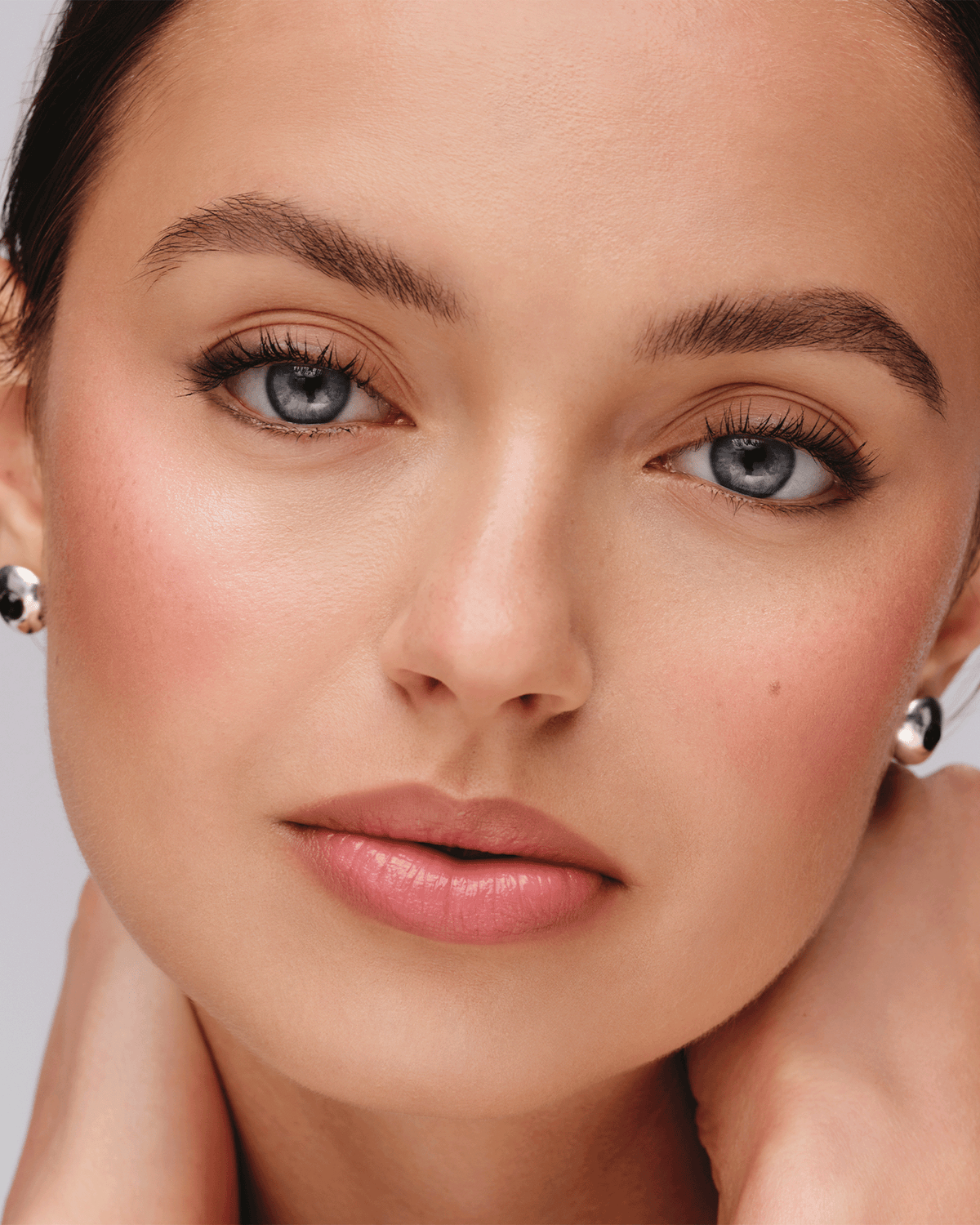Beauty close-up featuring Westman Atelier Petite Party products, with soft blush, luminous highlight, defined eyes, and a natural makeup finish.