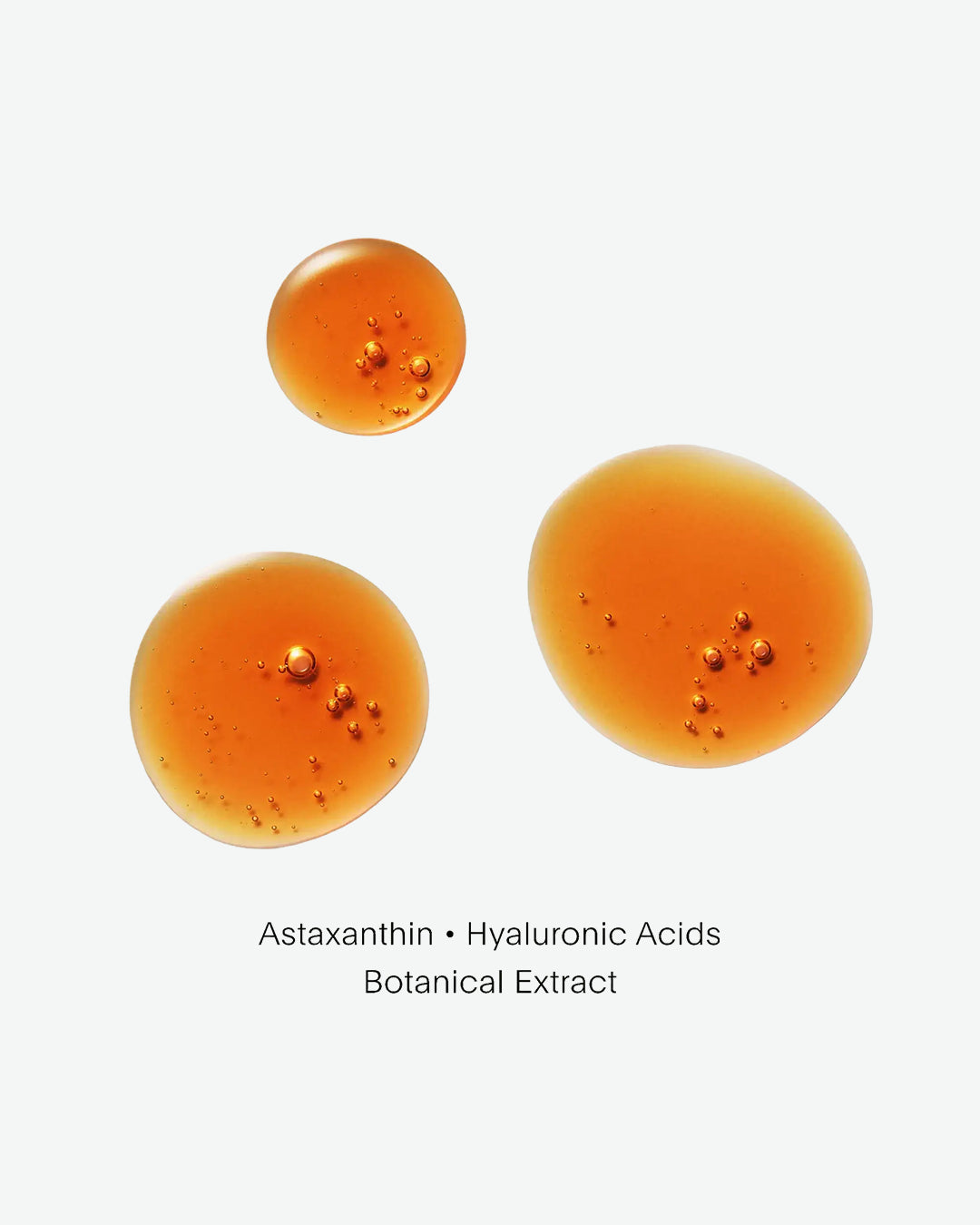 Three spherical droplets of a yellow-orange liquid on a white background, labeled with ingredients.