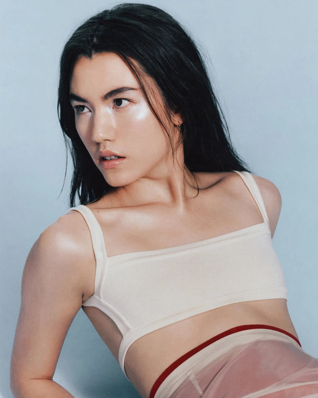 Woman wearing a beige bralette with thin straps against a light blue background