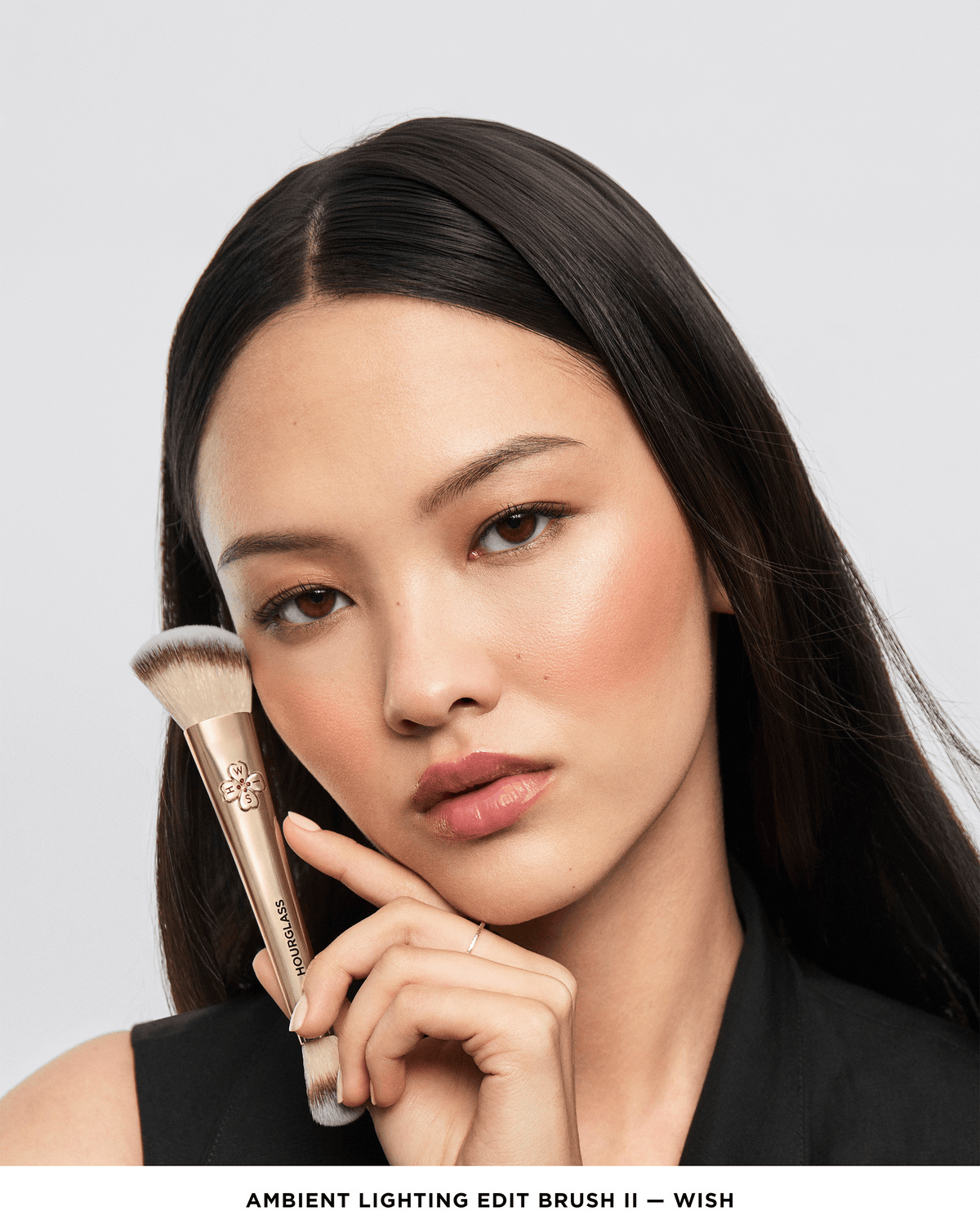 Model holding the Hourglass Ambient Lighting Edit Brush II – Wish beside her face, showcasing the gold double-ended design and wish charm.