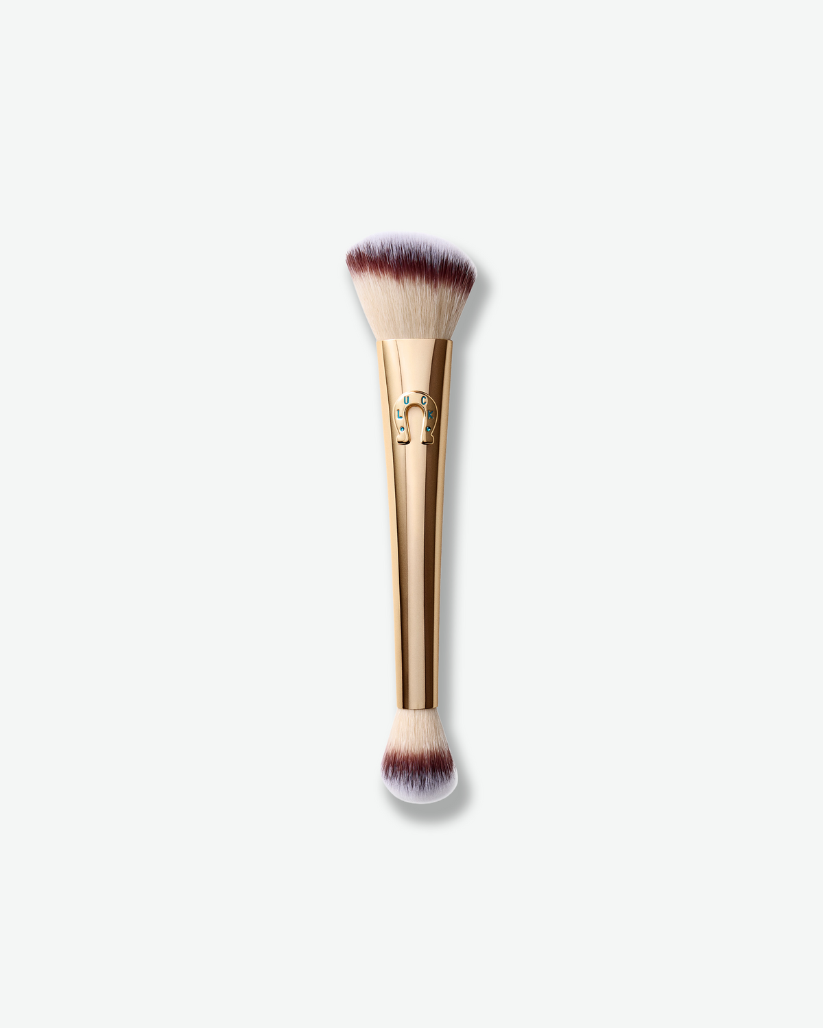 Hourglass Ambient Lighting Edit Brush II in Luck, a double-ended gold makeup brush with soft cream and burgundy-tipped bristles and a horseshoe charm detail.