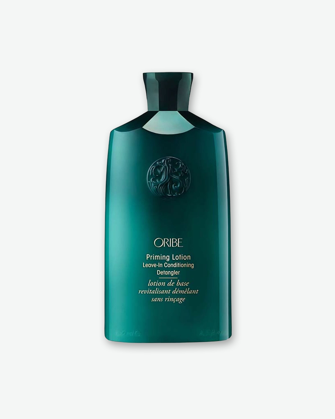 A studio product shot of an Oribe hair care bottle against a light gray background. The tall, custom-molded plastic bottle is a glossy, deep emerald green with a matching dark green cap. Near the top, the signature circular Oribe goddess emblem is embossed directly into the plastic. The gold text on the front reads 'ORIBE' in its signature serif font, followed by 'Priming Lotion Leave-In Conditioning Detangler'.