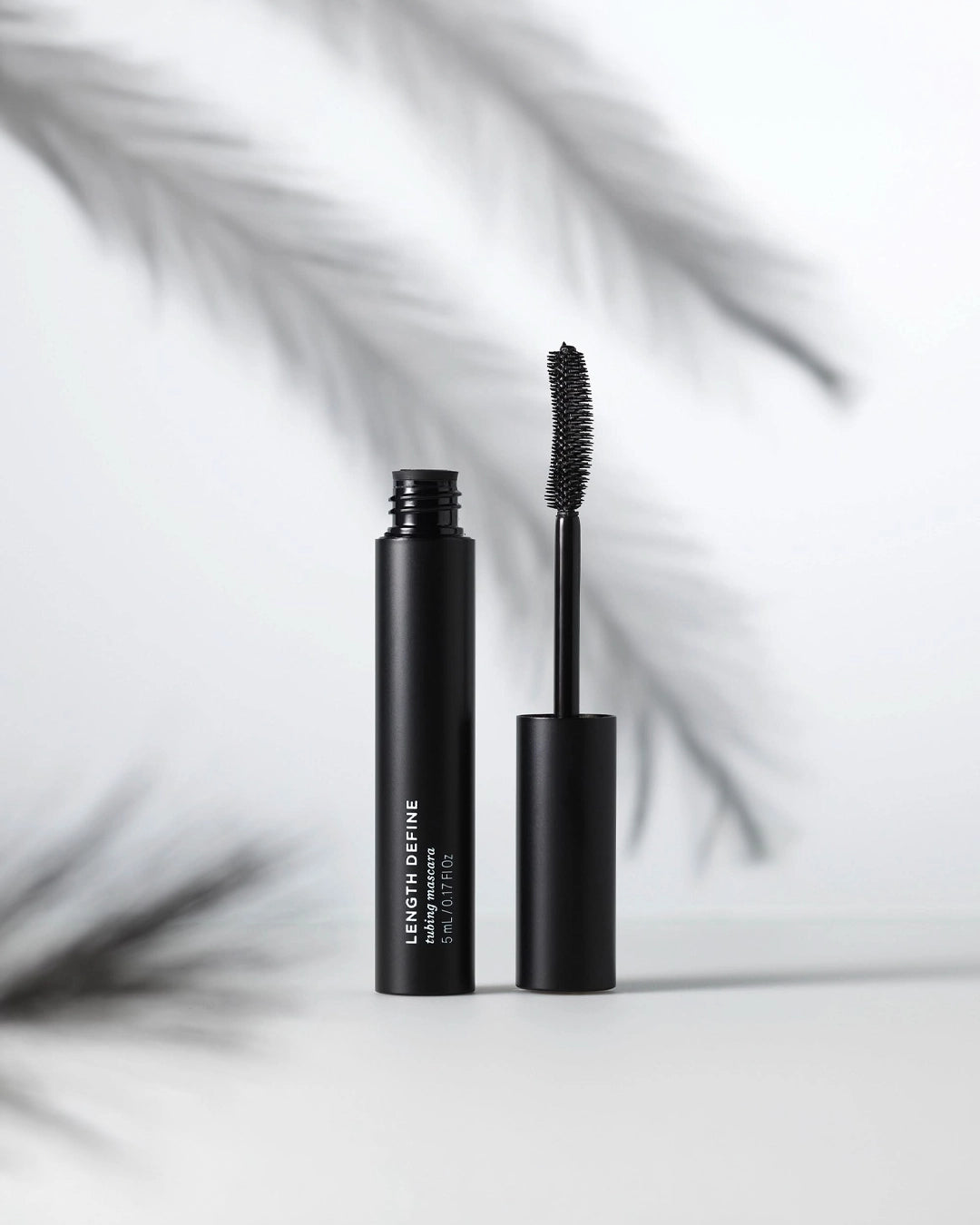 Black mascara with open cap on a light gray background