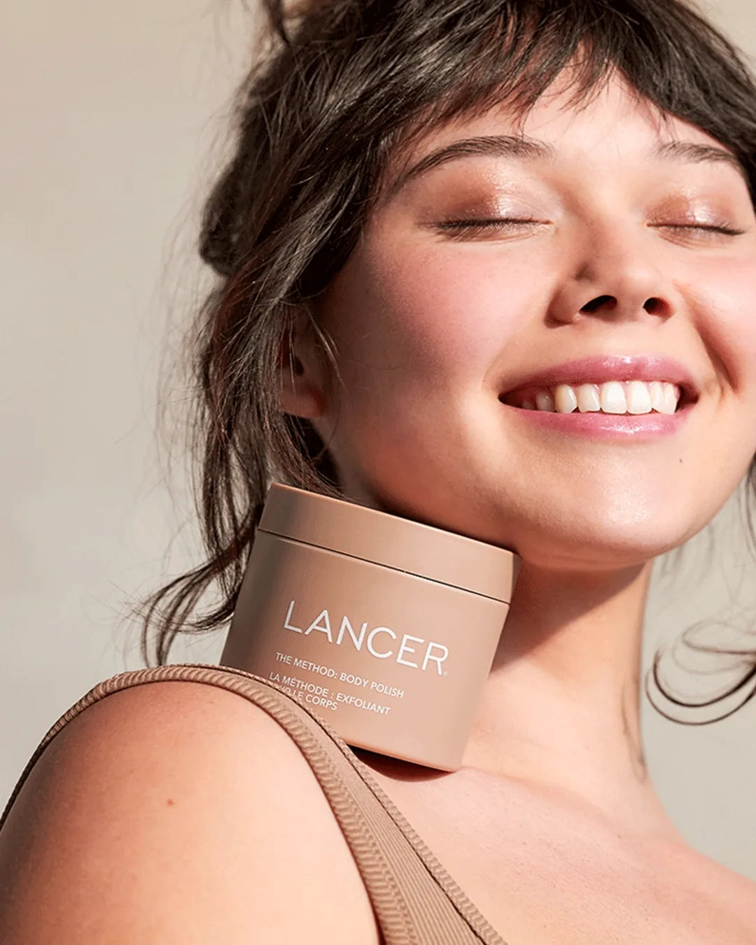 Woman holding a Lancer product with a neutral background