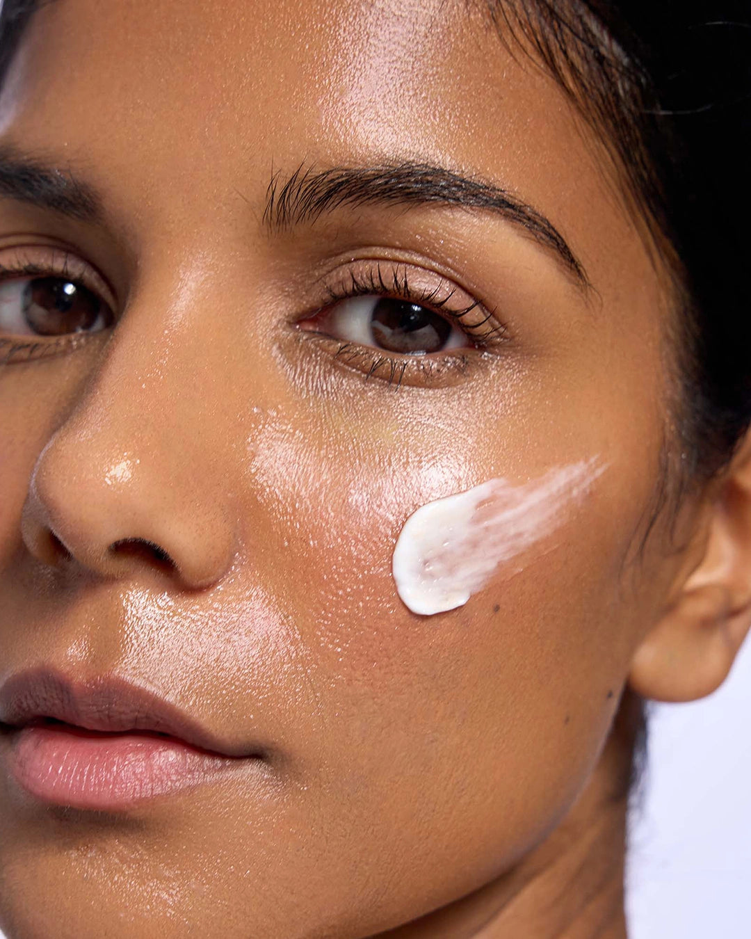 Close-up of a woman's face with a cosmetic product on her cheek