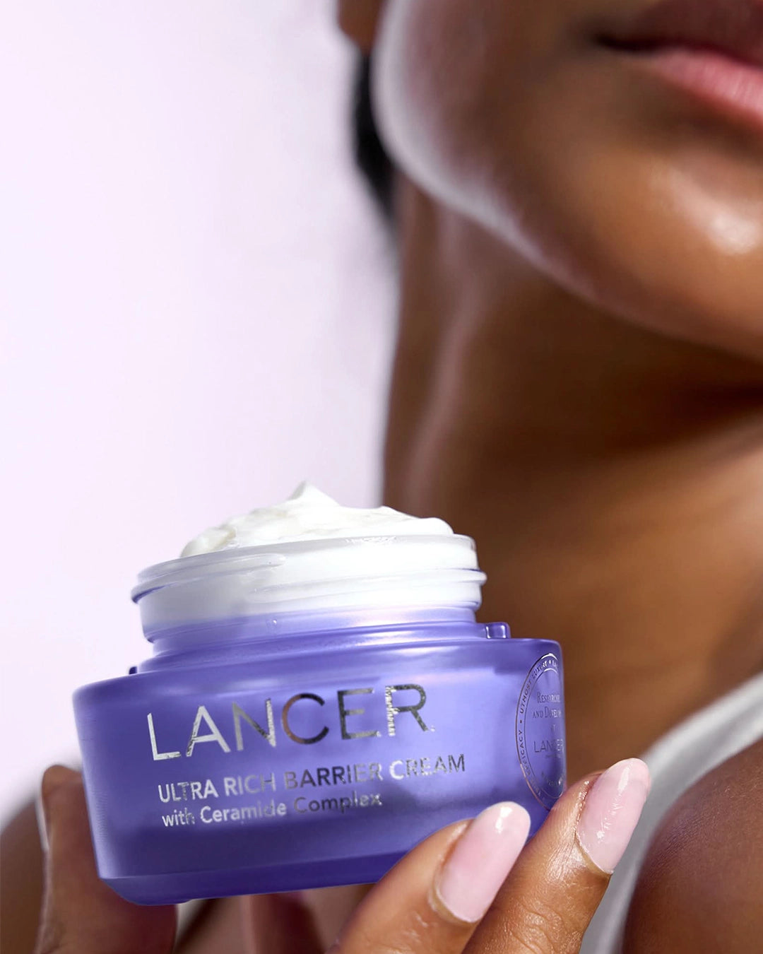 Lancer Ultra Rich Barrier Cream jar with cream on top, held by a person.