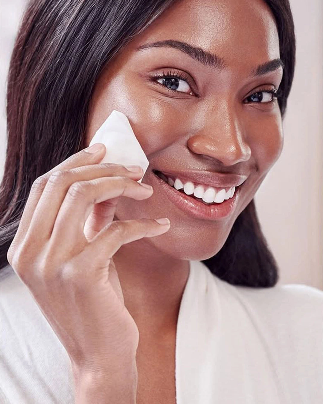 Woman applying a skincare product to her face with a white background