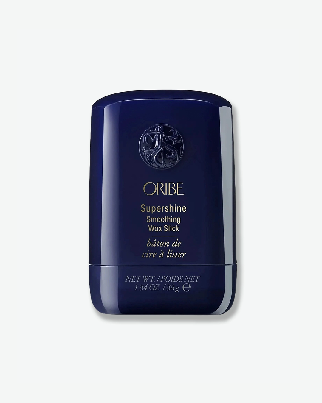 A product shot of an Oribe Supershine Smoothing Wax Stick container, centered against a plain light gray background. The curved, oval-shaped container is made of a glossy, deep midnight blue plastic with a matching pull-off cap. The upper portion of the cap features Oribe's signature circular embossed goddess emblem. Below it, the brand name "ORIBE", "Supershine Smoothing Wax Stick", and the French translation "bâton de cire à lisser" are printed in fine gold script. The smaller base twist-section at the bo