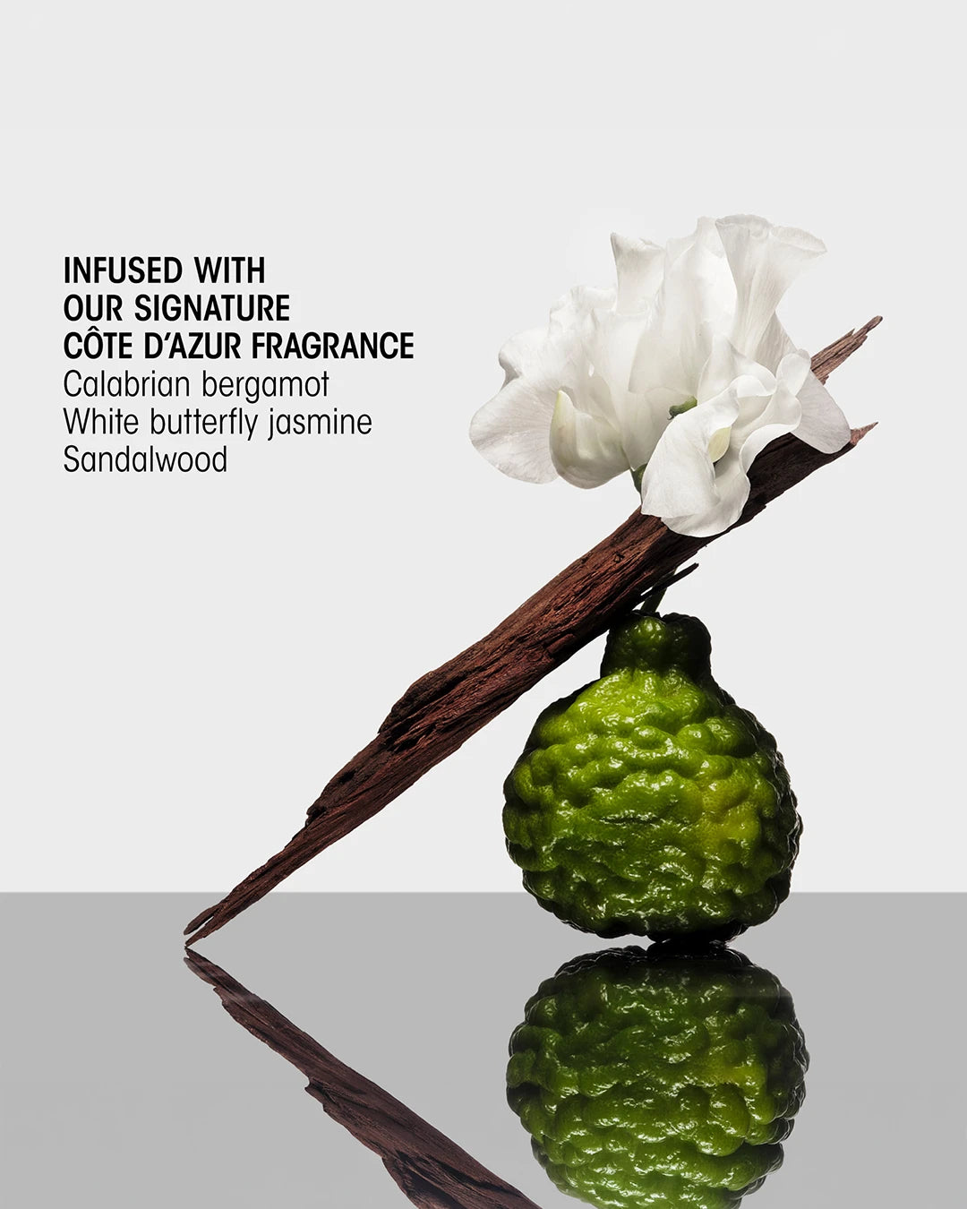 Vanilla bean, bergamot fruit, and jasmine flower on a reflective surface with text about Cète d'Azur fragrance.