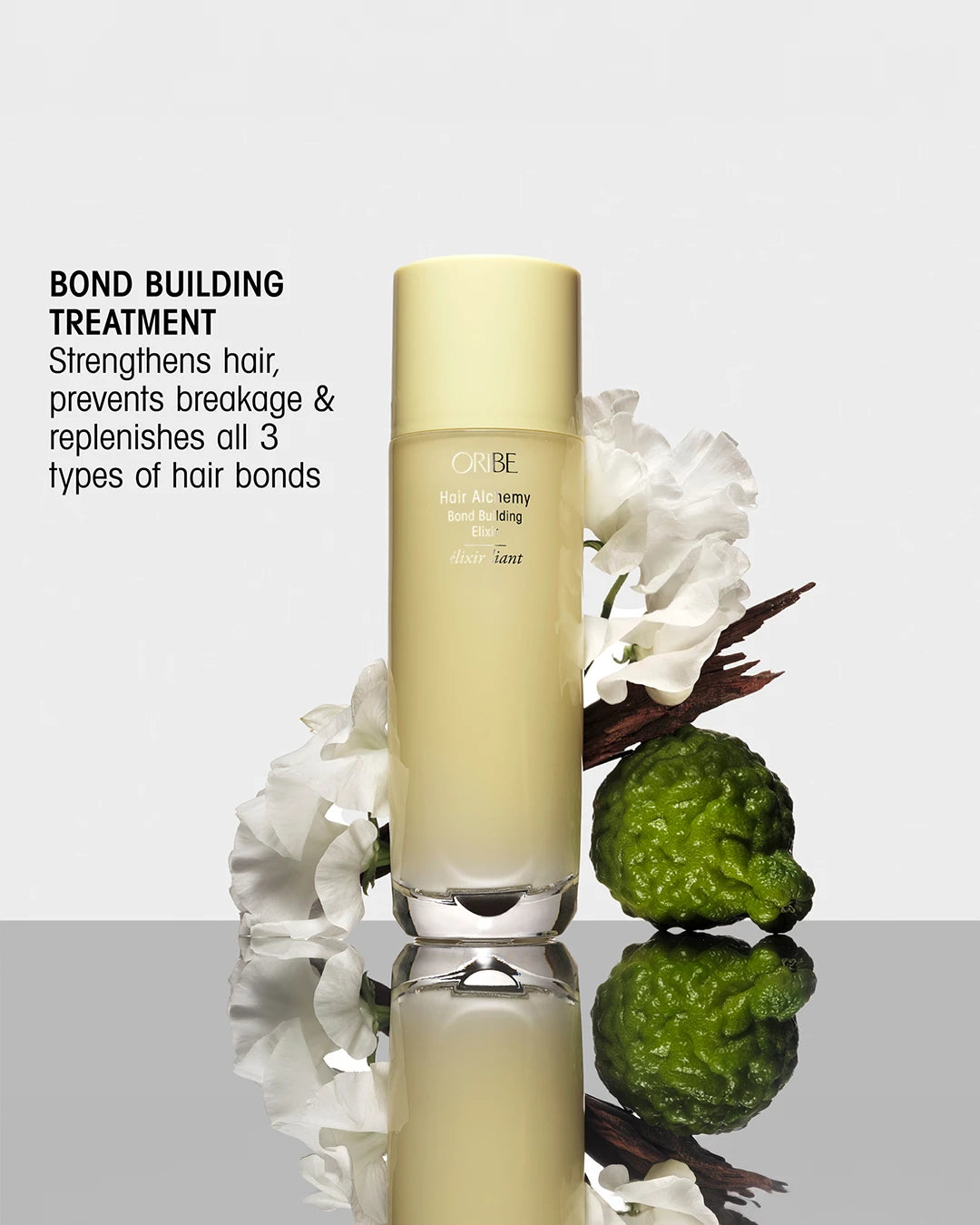 Hair care product with green fruit and white flowers on a reflective surface