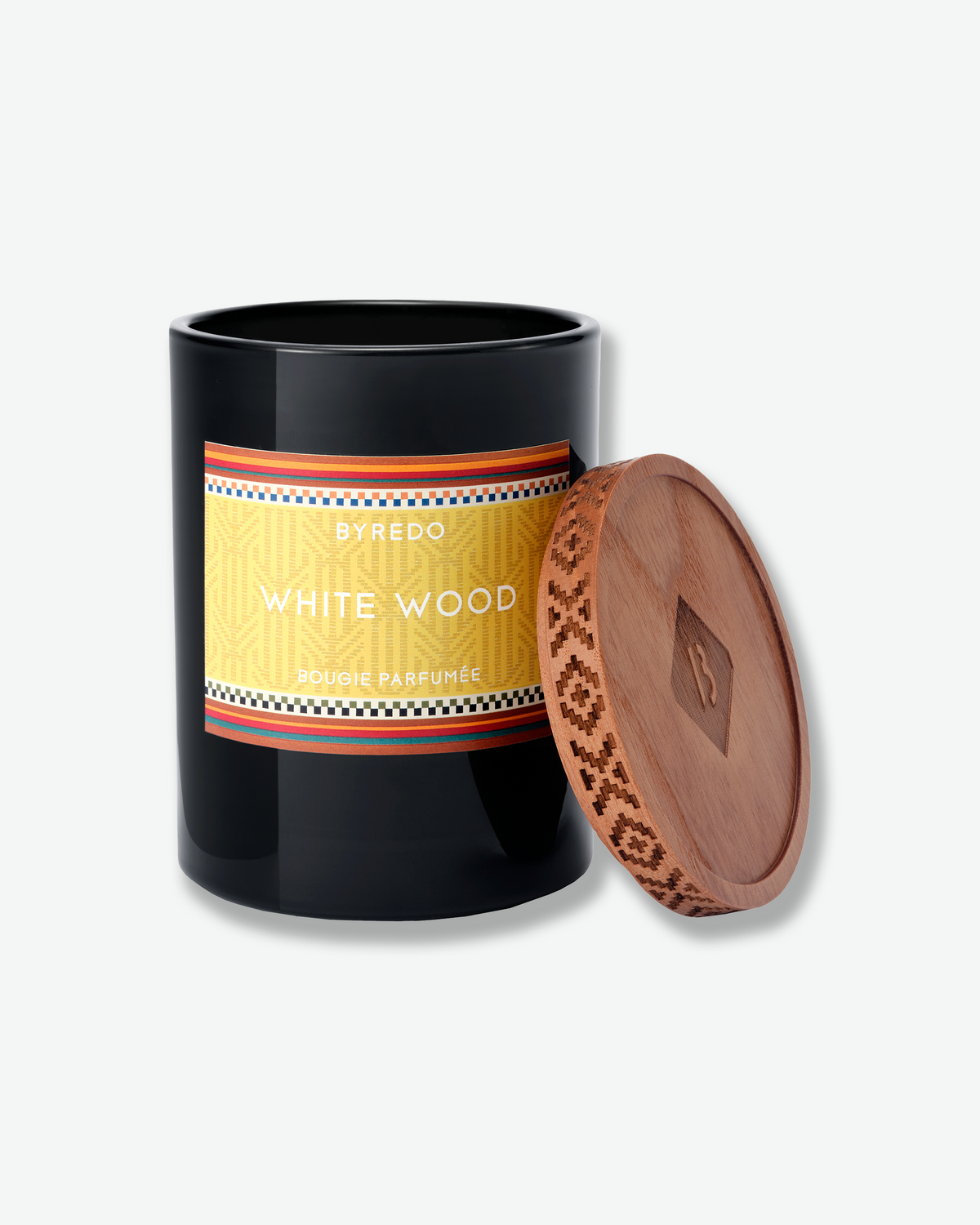 Open Byredo White Wood candle with its patterned wooden lid resting beside the black glass vessel.