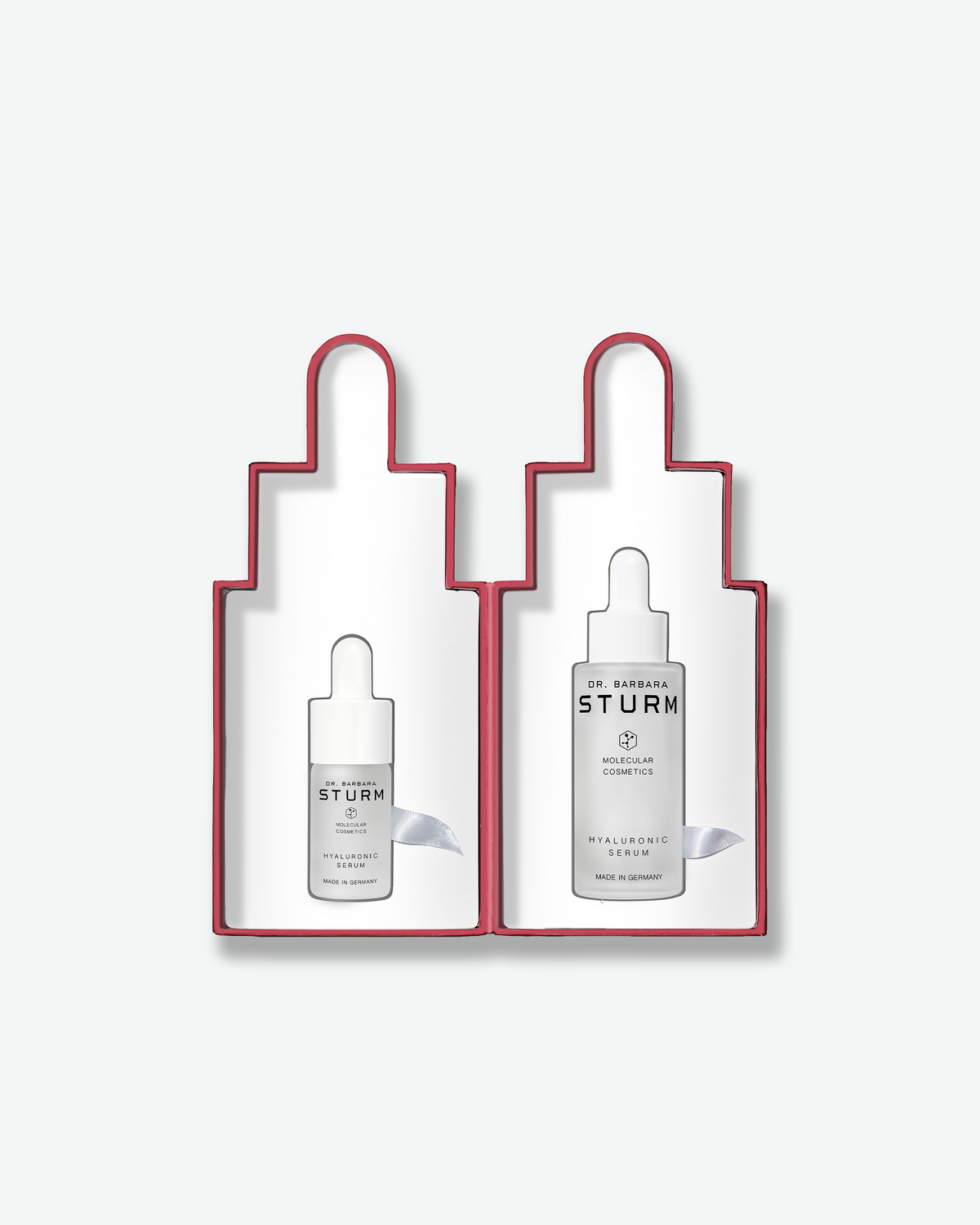 Dr. Barbara Sturm Home & Away Duo Hyaluronic Serum gift set displayed inside red dropper-shaped packaging with full-size and miniature Hyaluronic Serum bottles.