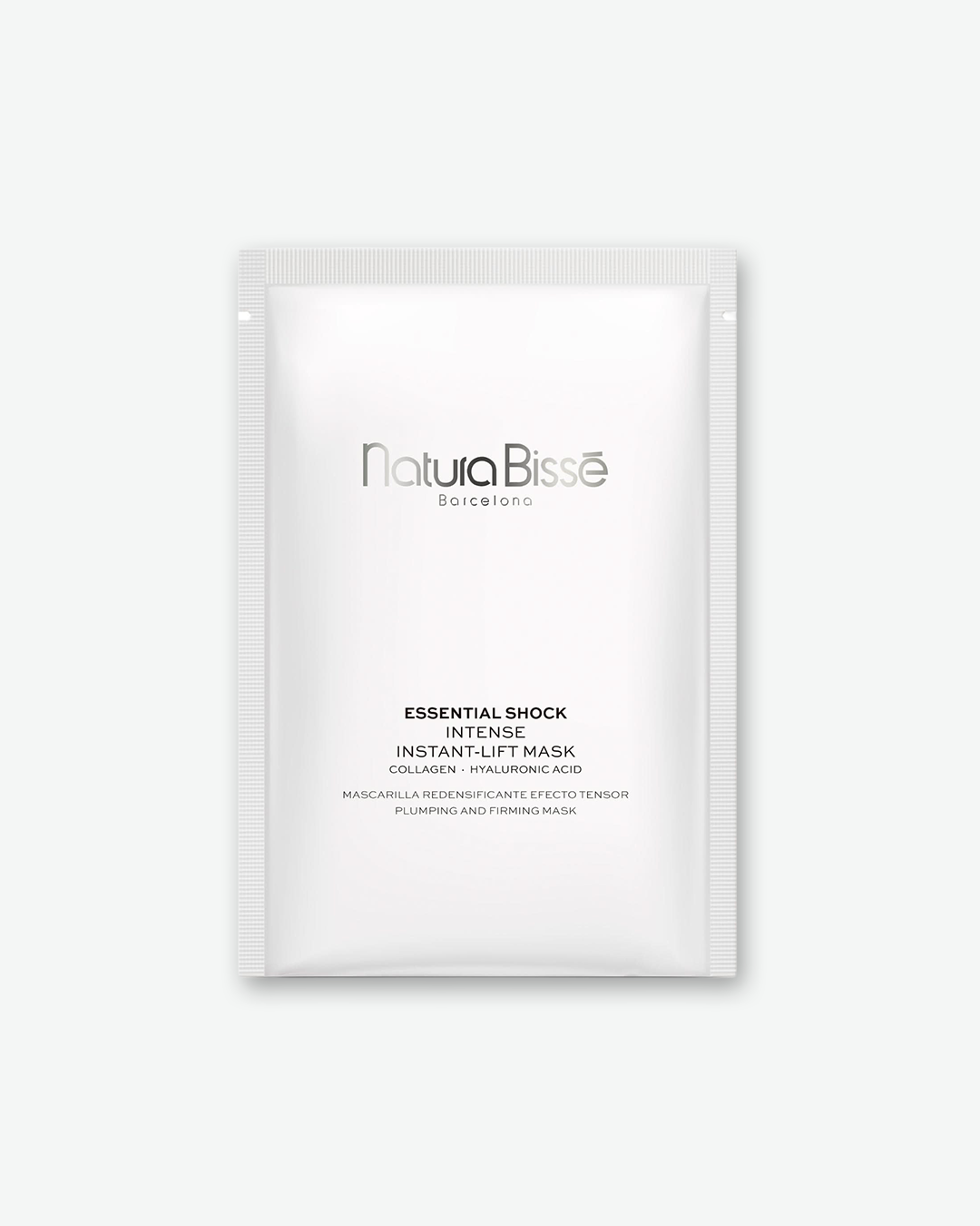 Front view of a rectangular, single-use skincare sachet in matte white with crimped, textured sealed borders on all four sides. The silver branding in the center reads "Natura Bissé Barcelona". Underneath the logo, the black text identifies the item as: "ESSENTIAL SHOCK INTENSE INSTANT-LIFT MASK COLLAGEN • HYALURONIC ACID", followed by "MASCARILLA REDENSIFICANTE EFECTO TENSOR PLUMPING AND FIRMING MASK". The sachet stands vertically against a plain white background.