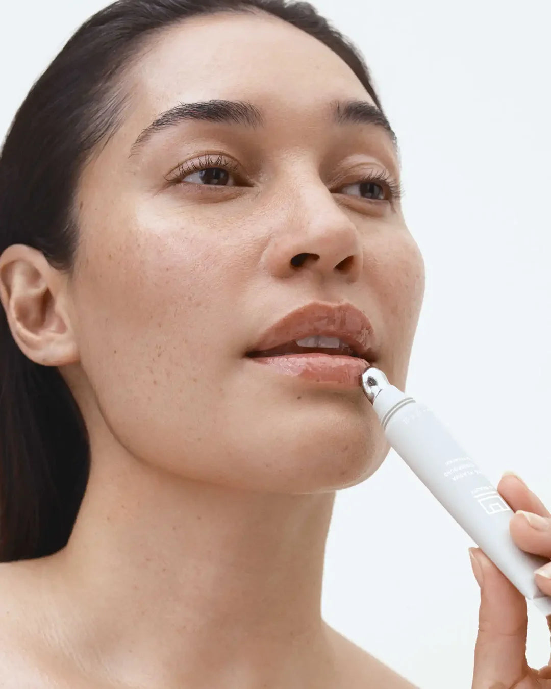 Woman using a lip balm against a white background