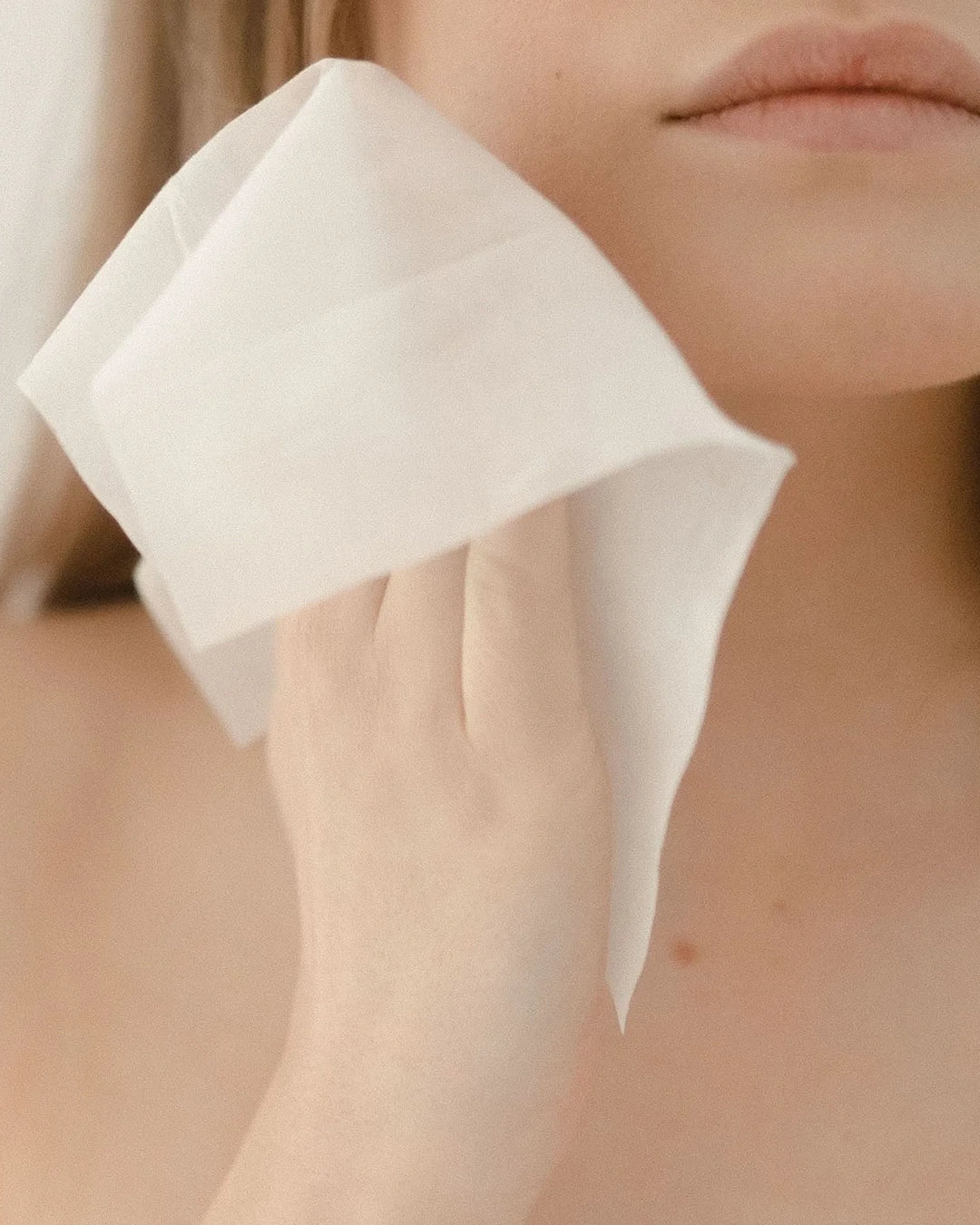 Person using a white cotton pad on their face