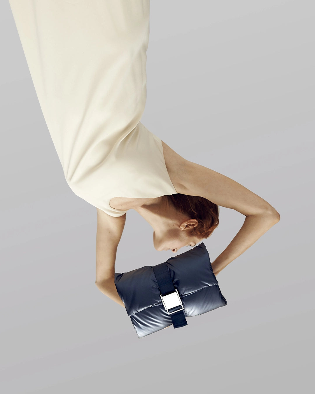Person holding a black clutch bag against a plain background