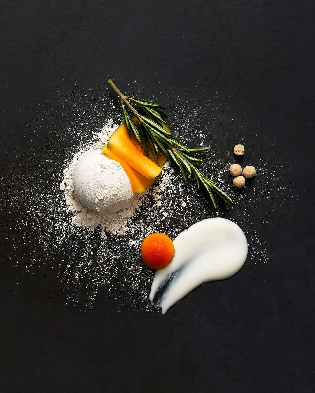 Ingredients including flour, eggs, and cream on a black surface