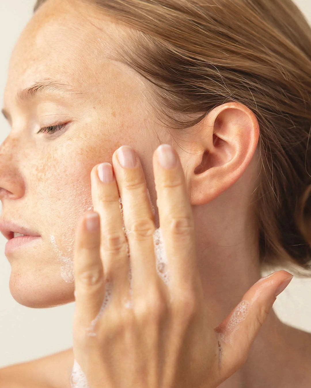 Woman applying a skincare product to her face with her hand.