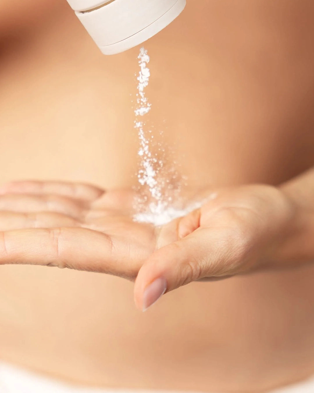 Person pouring white powder from a container onto their palm.