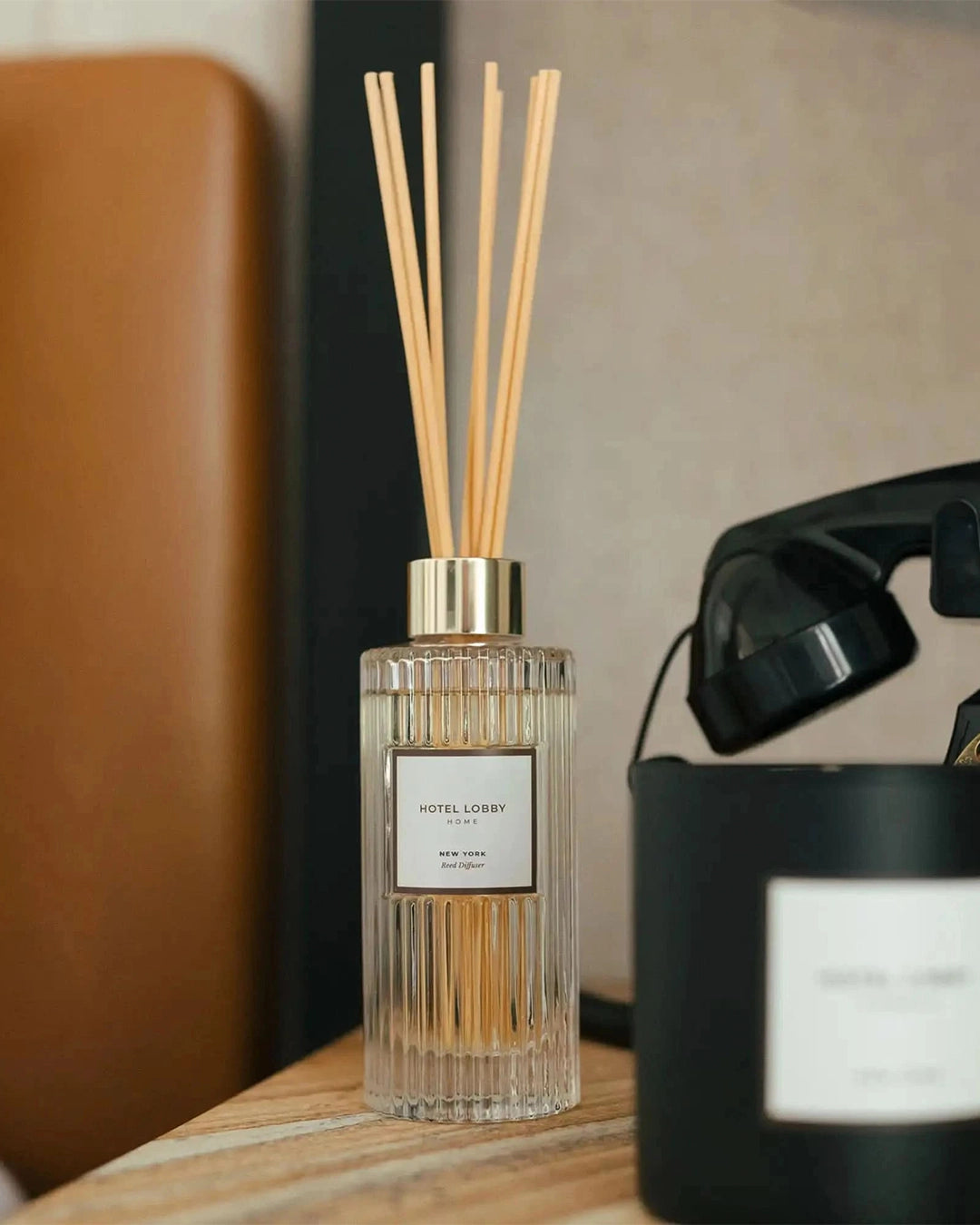 Diffuser with wooden sticks on a table next to a black phone.