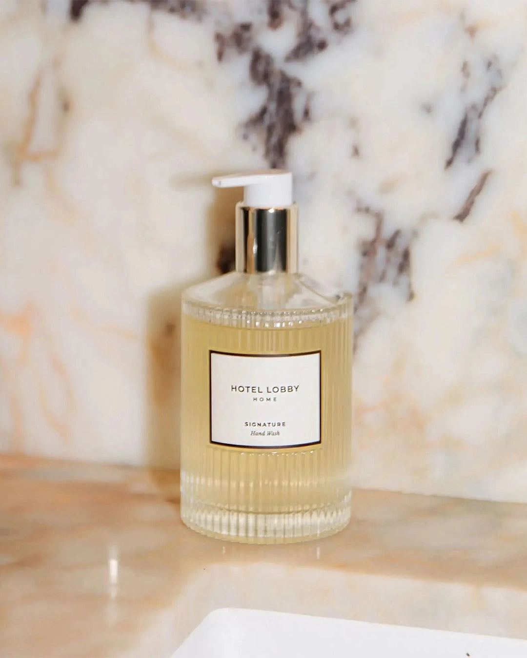 Hand Wash bottle labeled 'Hotel Lobby' on a marble surface