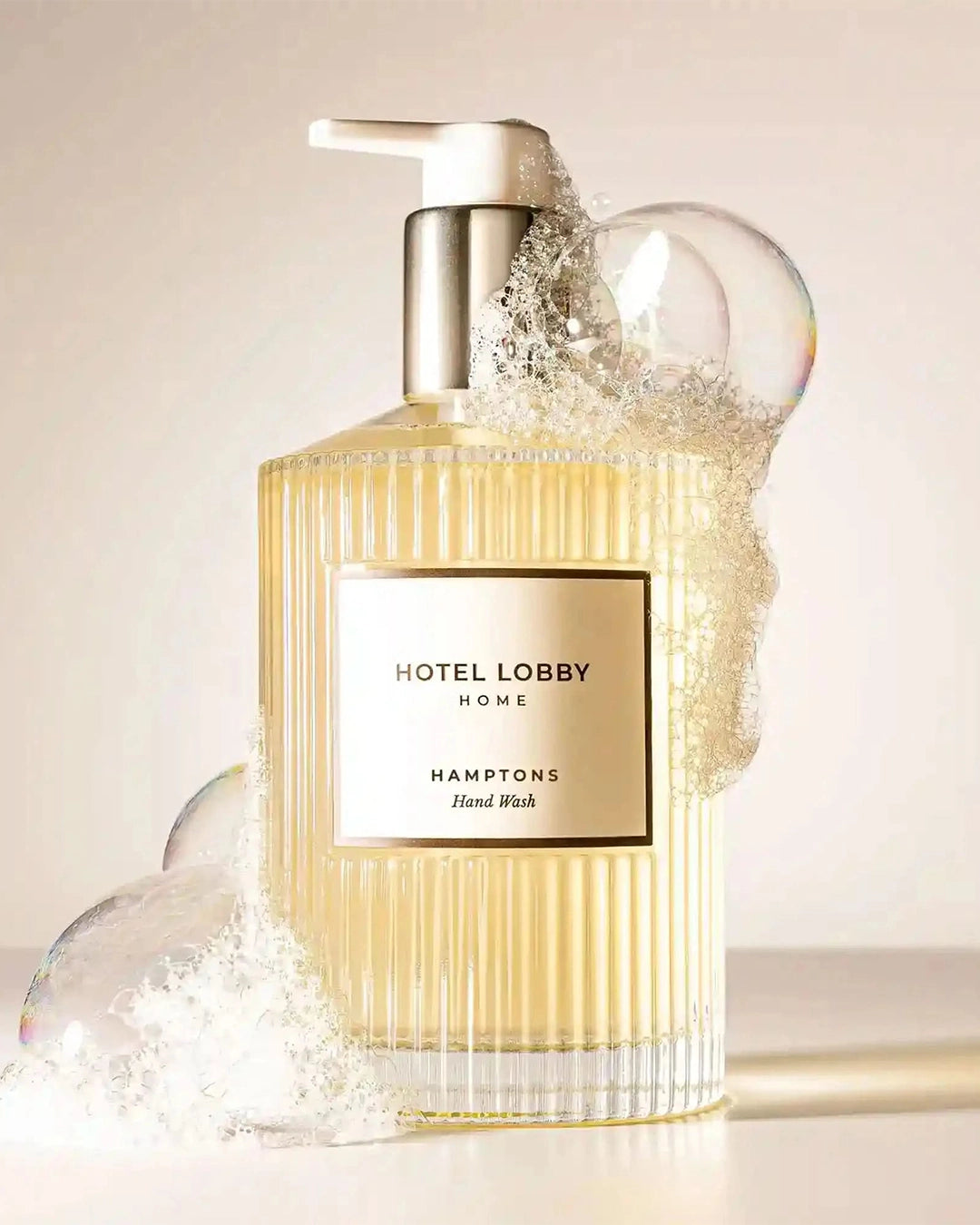 Hand wash bottle labeled 'Hotel Lobby Home' with a pump and bubbles on a light background