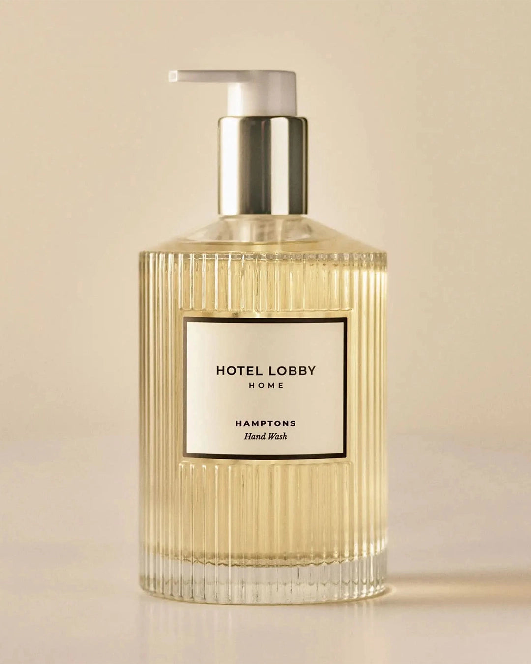 Hand wash bottle with pump labeled 'Hotel Lobby Home' on a beige background