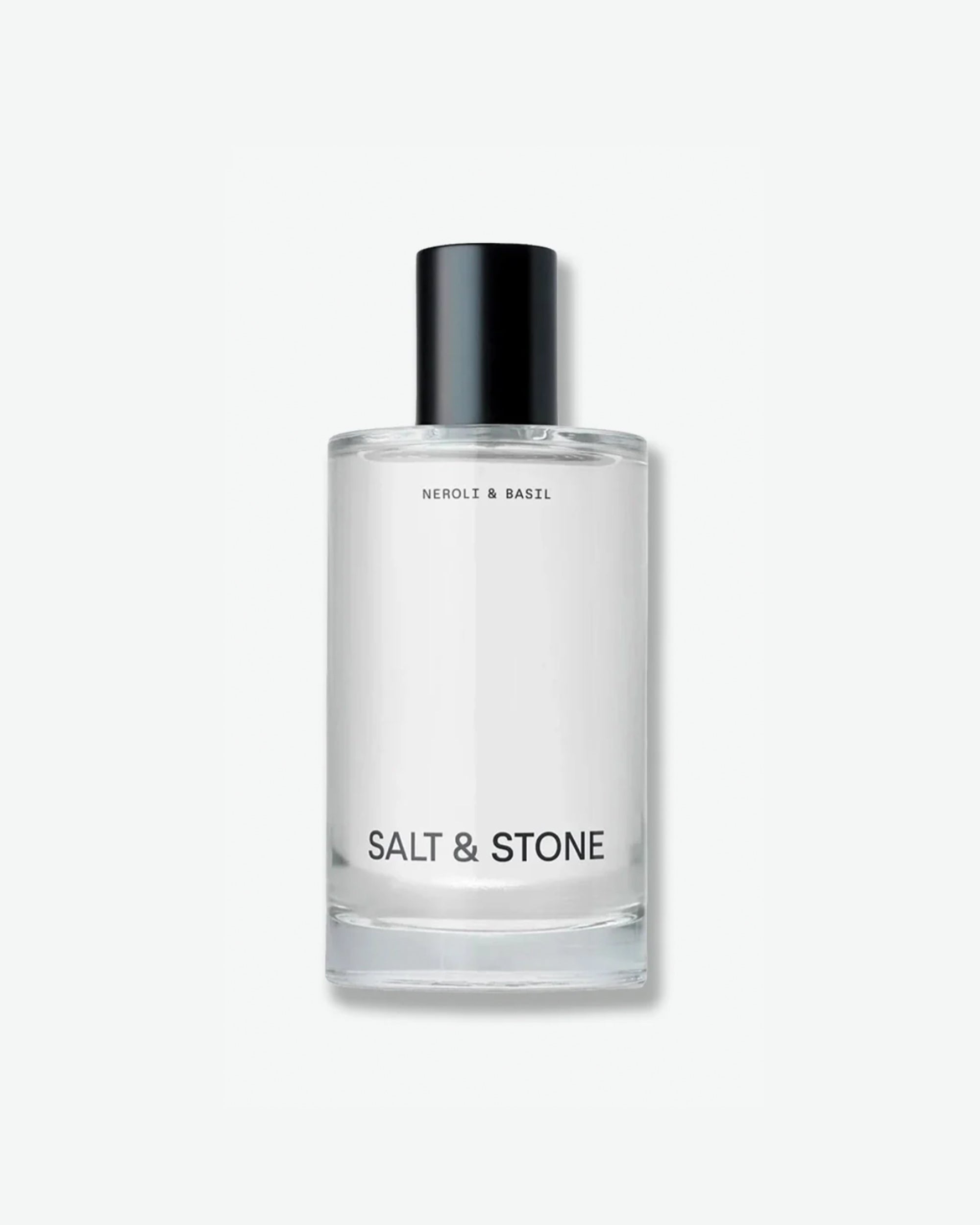 Salt & Stone Neroli & Basil product in a minimalist clear glass bottle with a black cylindrical cap and clean black typography, isolated against a light grey background.