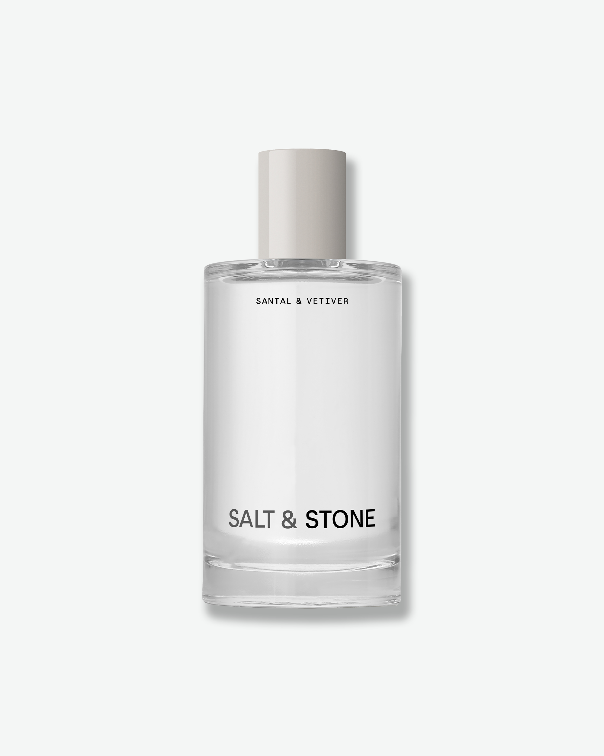 A clear glass perfume bottle with a light gray cap, labeled 'SANTAL & VETIVER' and 'SALT & STONE', centered on a light gray background.